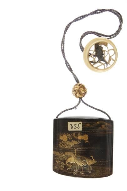 Inro à trois cases en laque mura nashiji sur fond de ro-iro décoré en hira maki-e de laque or, noir et togidashi de grues posées au bord d'un ruisseau bordé de chrysanthèmes dans un paysage montagneux. Intérieur en laque fundame et rouge. Signé Kanko Bunryusai.  H. 7,1 cm. Ojime en ivoire à décor de crapaud. Manju en ivoire à décor ajouré et incrusté de shibuichi, grue parmi les millets. (Petite gerce). 