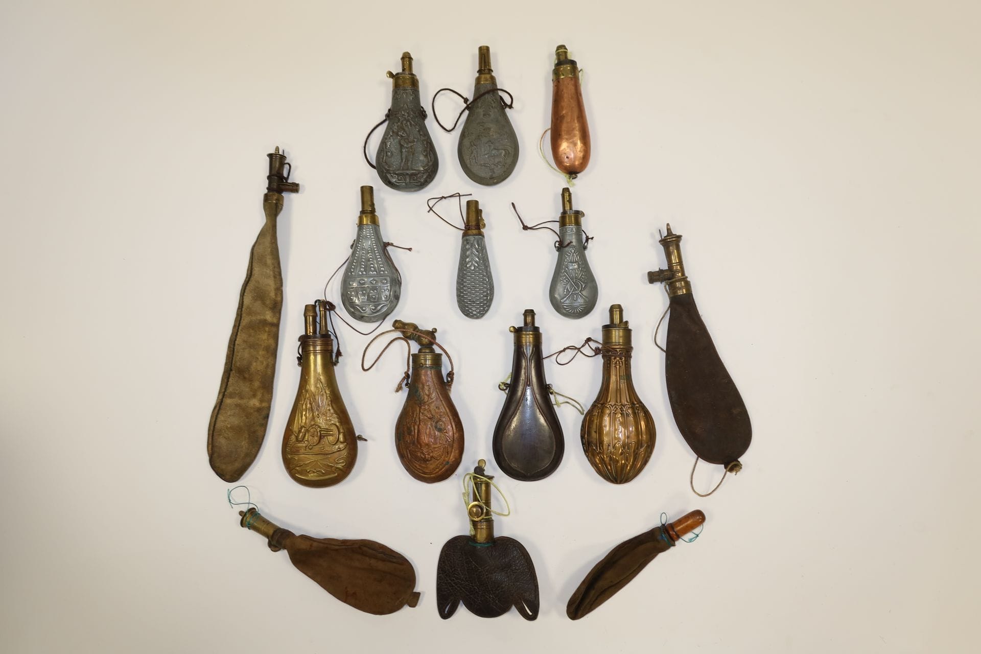 Lot of ten powder flasks, five in white metal and five in copper. 
Decor of hunting and plants. Brass spouts, some of them measuring.
Five skin lead flasks are attached.
A.B.E



