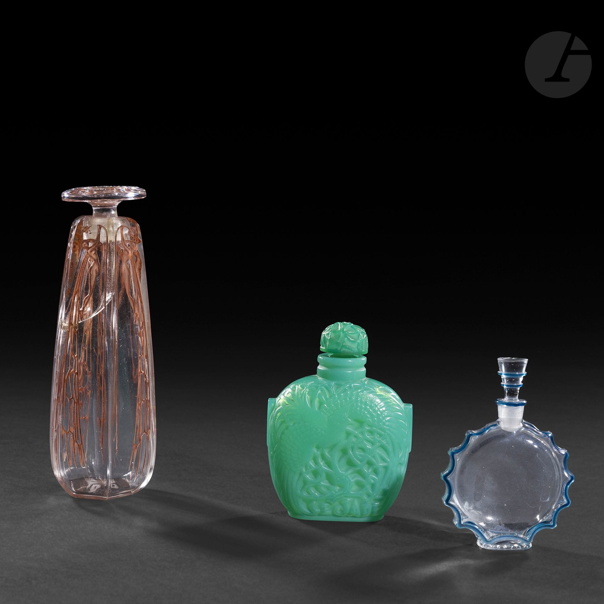 RENÉ LALIQUE (1860-1945) – 3 ŒUVRES
RENÉ LALIQUE (1860-1945) POUR PARFUMS ROGER & GALLET 
Le Jade, le modèle conçu le [7 décembre 1926]
Rare flacon de parfum à l’évocation d’un tabatière chinoise. La base en verre teinté vert dans la masse soufflé-moulé, le bouchon en verre vert teinté dans la masse moulé-pressé (Réf. Marcilhac Roger & Gallet - 15). Monogrammé R. L. France, à la pointe sous la base, marqué ROGER & GALLET Paris dans le moule à la base sur l’une des faces, titré Le Jade sur l’autre face à la base dans le moule. H. 8 cm
RENÉ LALIQUE (1860-1945) POUR PARFUMS FRANÇOIS COTY 
Cyclamen, le modèle conçu vers [1912]
Flacon de parfum en obus facetté ; le bouchon circulaire. La base en verre soufflé-moulé, le bouchon en verre moulé-pressé (Réf. Marcilhac Coty - 22). Les décors entièrement patinés ocre-rouge d’origine. Très importante fêlure au trois-quarts en démarrage du col et se poursuivant sur le corps. Signé R. LALIQUE France vers la base, marqué COTY Paris Cyclamen sur la bouchon et COTY Paris sous la base. H. 13,5 cm
RENÉ LALIQUE (1860-1945) POUR PARFUMS FRANCOIS COTY 
Requête, le modèle conçu vers [1944]
Flacon de parfum à bordure dentelé. La base en verre soufflé-moulé, le bouchon en verre moulé-pressé (Réf. Marcilhac Worth – 226). Les bordures émaillées bleu. Signé LALIQUE France sous la base, monogrammé W sur le bouchon. H. 7,3 cm