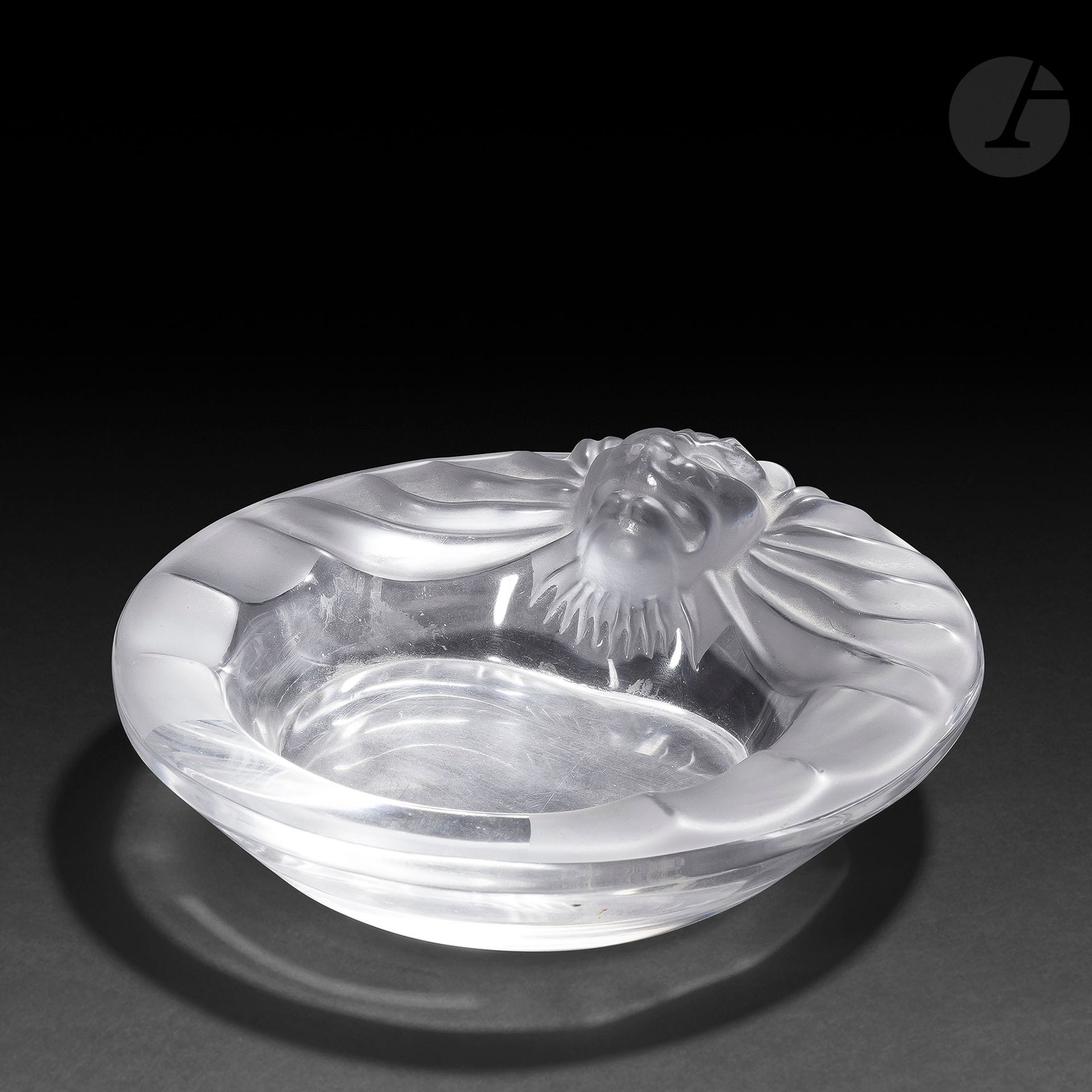 MAISON LALIQUE – MODÈLE DE MARC LALIQUE (1900-1977)
Tête de lion, le modèle créé en [1960]
Coupelle. Épreuve en cristal moulé-pressé, et en partie satiné (Réf. Catalogue général Lalique 2012 : 1074300). Signé LALIQUE ® France en lettres cursives, à la pointe sous la base. H. 5,5 cm – D. 14,5 cm