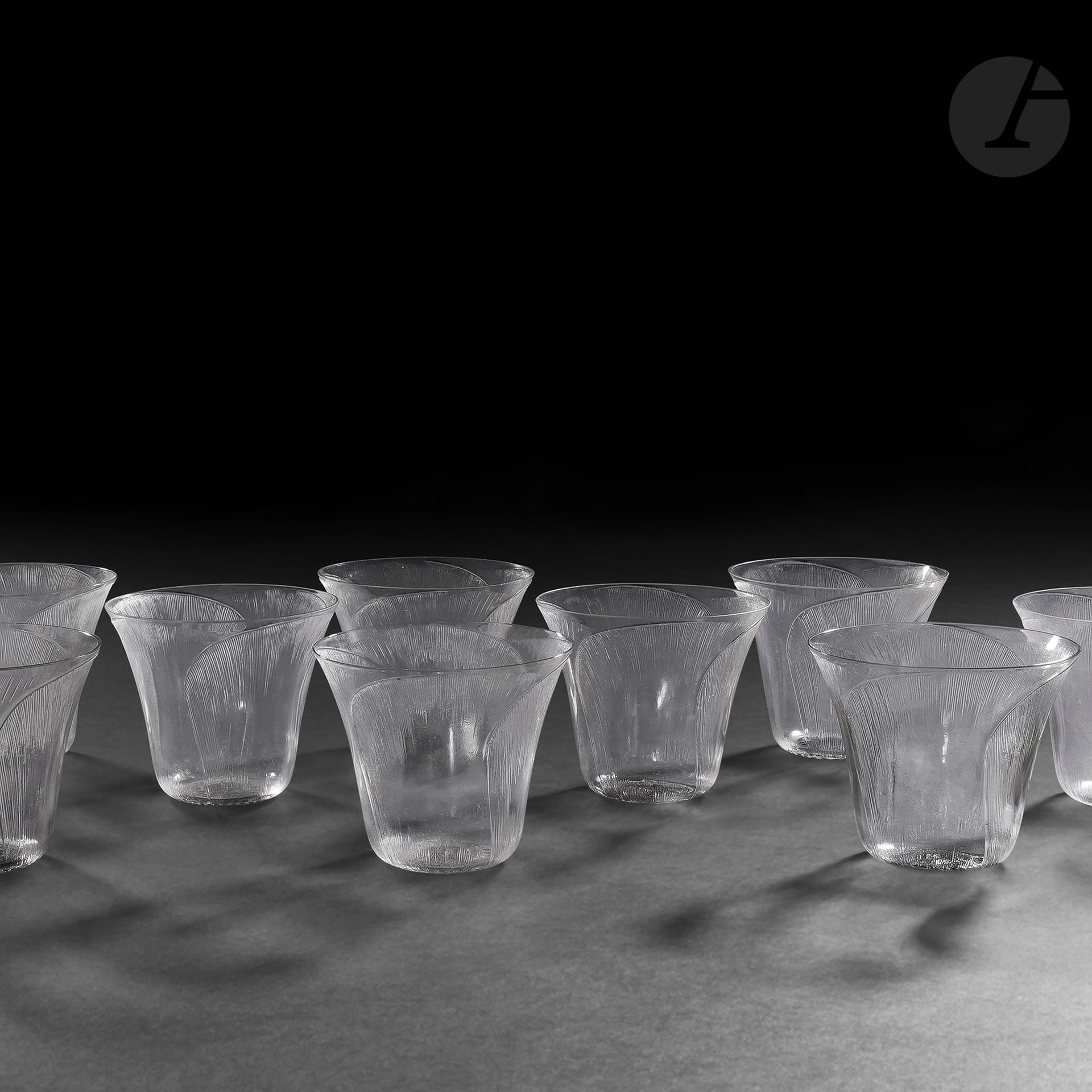 RENÉ LALIQUE (1860-1945) 
Pavot, le modèle créé en [1922]
Suite 11 gobelets. Épreuves en verre soufflé-moulé et, en partie, émaillé noir (Réf. Marcilhac 3407). Deux infimes égrenures sur le pourtour de l’un des verres. Deux verres signés R. LALIQUE, l’un numéroté 3407 au revers. H. 7,5 cm
On y joint :
RENÉ LALIQUE (1886-1945) 
Lotus, le modèle créé en [1924]
Gobelet. Épreuve en verre soufflé-moulé et, en partie, émaillé noir (Réf. Marcilhac 3406). H. 7,5 cm