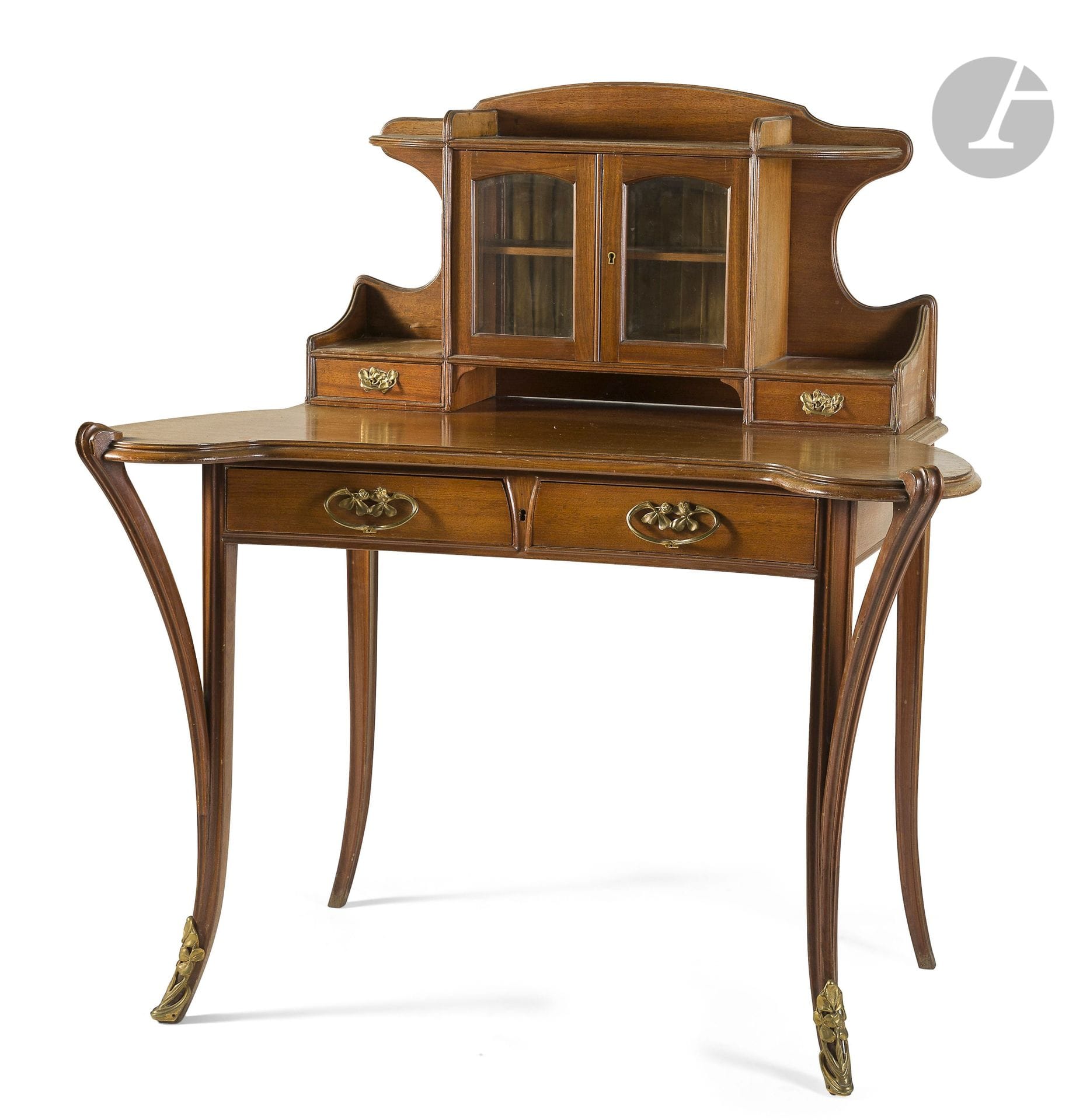 LOUIS MAJORELLE (1859-1926)
Bureau dit Bonheur du jour en acajou et placage d’acajou. Le plateau de l’entablement présente des angles en excroissance et repose sur des pieds moulurés curvilignes et terminés à l’avant par des sabots en bronze doré. La ceinture s’ouvre par deux tiroirs aux prises d’origine en bronze doré. La partie haute s’ouvre par deux portes vitrées et deux tiroirs également complets de leurs prises en bronze d’origine. Époque Art nouveau. Insolations, petits accidents et manques épars. H. 120 cm – L. 113 cm – P. 68 cm

Bibliographie :
Majorelle Nancy – Catalogue commercial d’époque. Une bureau identique reproduit dans cette publication (sans pagination).