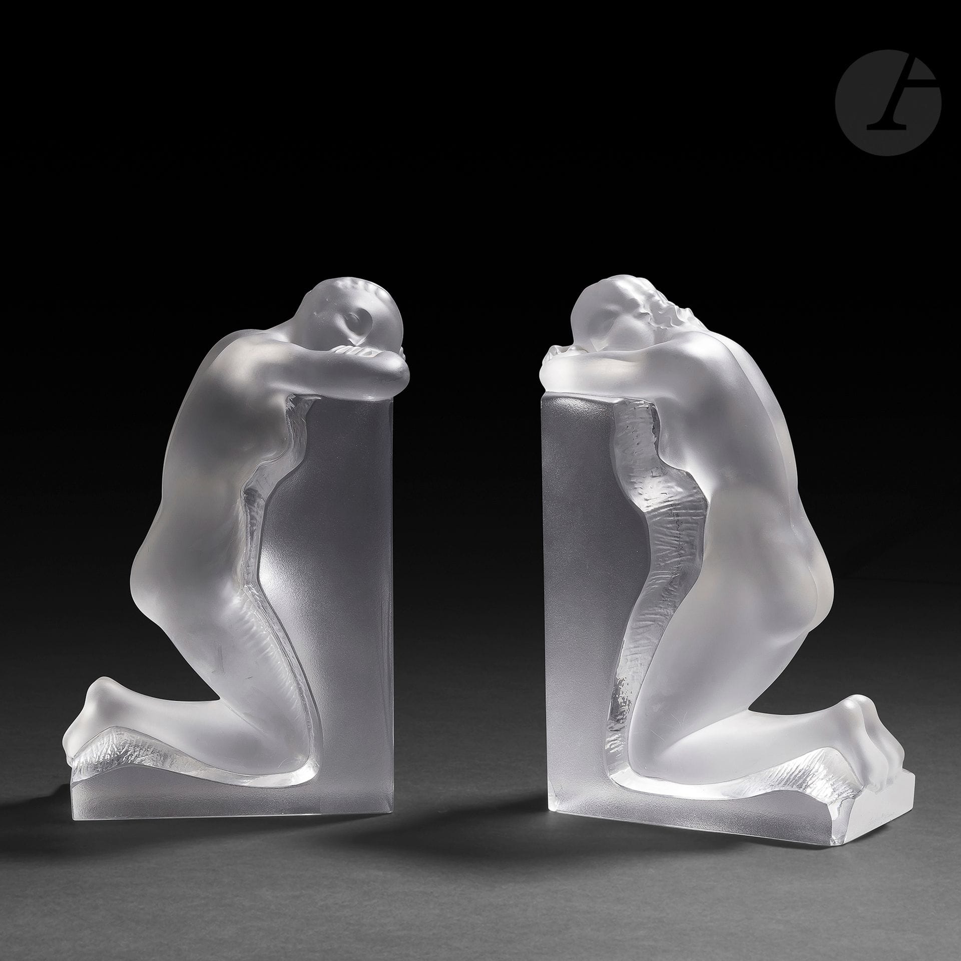 MAISON LALIQUE – MODÈLE DE MARC LALIQUE (1900-1977)
Rêverie, le modèle créé en [1948]
Paire de serre-livres. Épreuves en cristal moulé-pressé, et en partie satiné (Réf. Catalogue général Lalique 2012 : 1185 000). Deux éclats dont un restauré sur la base d’un serre-livre. Chacun signé LALIQUE ® France en lettres cursives, à la pointe sur la base. Chaque serre-livre : H. 22,4 cm – L. 14,9 cm – L. 9,5 cm