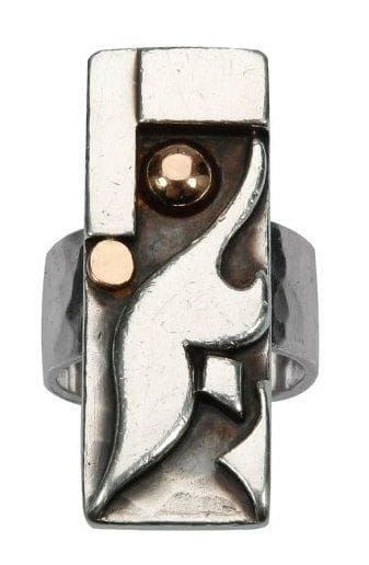 Jean DESPRES (1889-1980)
Très rare bague moderniste en argent à longue et étroite plateforme décentrée sur un large anneau. Décor d'une forme libre et de barrettes perpendiculaires, agrémenté d'une pastille et d'une demi-sphère en or rose, le tout sur fond martelé. Signée J. DESPRES à la pointe sous la plateforme et porte les poinçons de Maître orfèvre et de titre sur l'anneau. Poids: 18 g