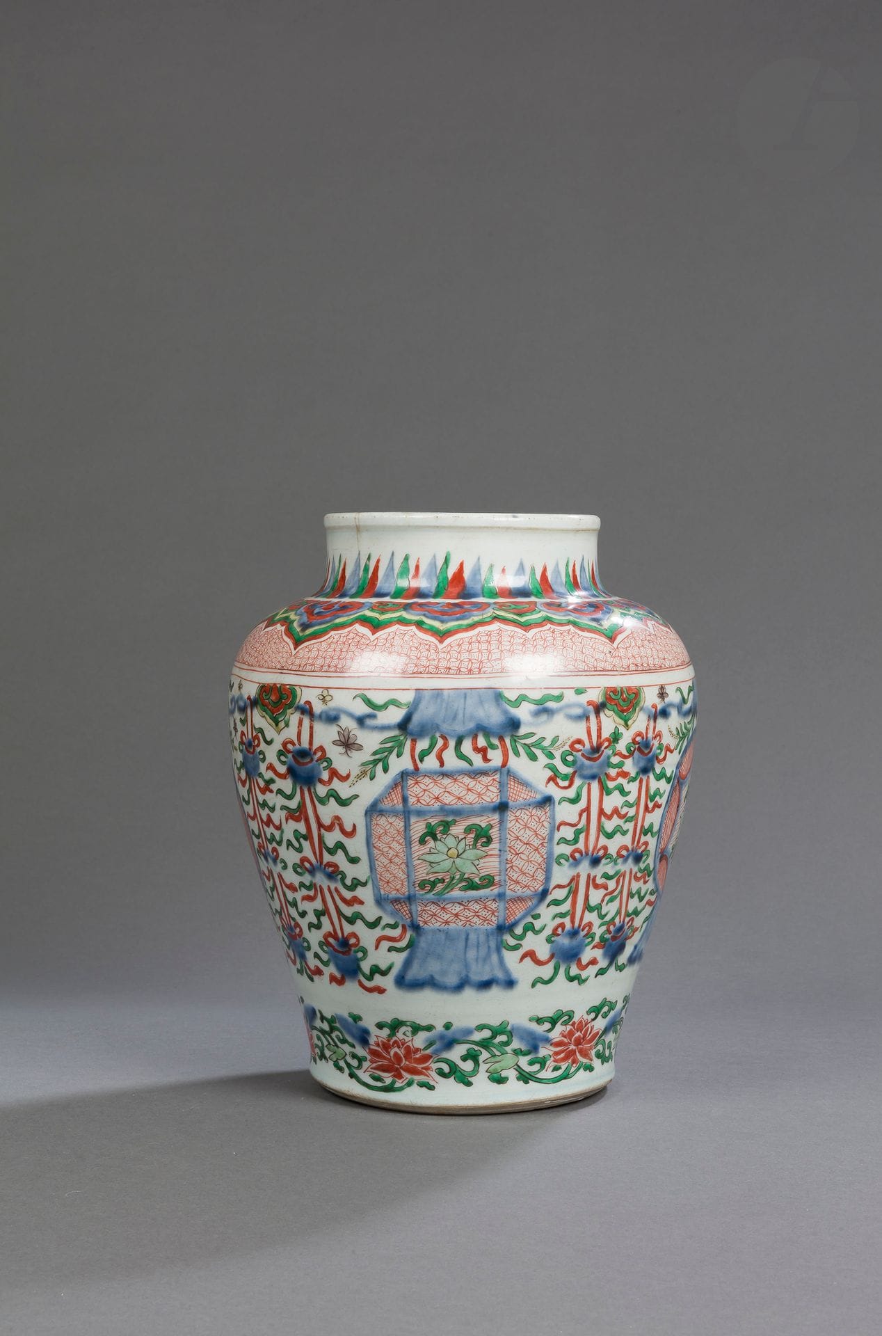Porcelain baluster vase with five-color wucai-五彩 lantern decoration, China, Transitional period, mid-17th century
The body decorated with underglaze blue enameled trimmings connecting ruyi heads and canopies, around which small butterflies fly. Hanging from it are four pairs of ribboned cords linking Buddhist emblems and four lanterns, two rounded and two with cut-off sides, decorated in their center with a lotus flower. The shoulder is decorated with a frieze of ruyi heads above a stylized background. Banana leaves decorate the neck and lotus flowers and scrolls the foot.
Height : 30 cm
Cracks and a chip on the neck, pierced bottom.

十七世纪中期 - 五彩颈如意蕉叶纹腹花卉灯笼纹瓶

