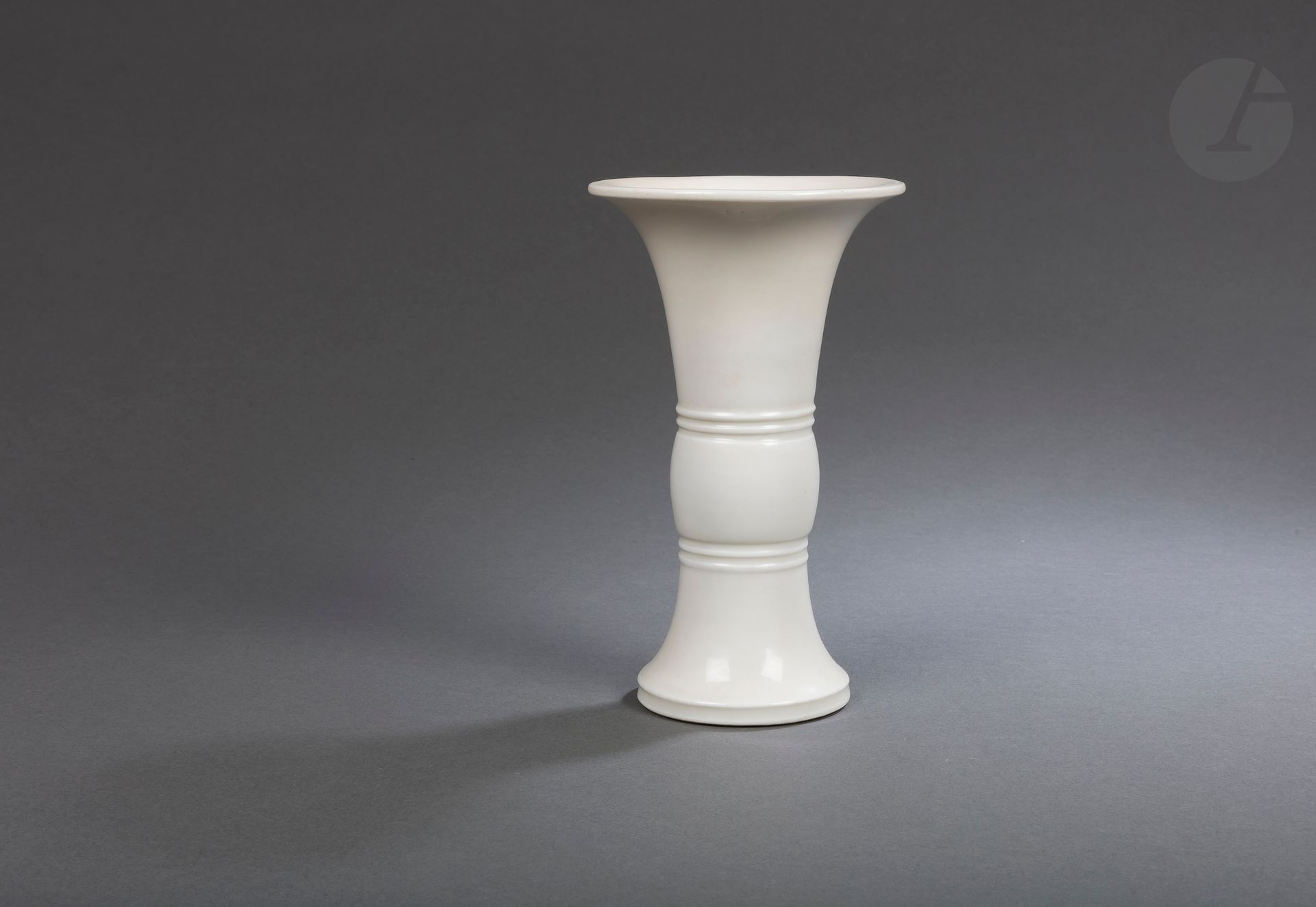 Chinese white porcelain gu vase, Dehua, China, Kangxi period (1662-1722)
Covered with an ivory glaze, its shape is inspired by archaic gu bronzes whose middle part is formed by a cylindrical bulb inserted between two rings in relief.
Height : 22 cm

Provenance: 
Spink &amp; Son label.

The gu - 觚 was originally a vase used for libations and intended to hold fermented drinks. Classically, the top is flared, the middle has a medial bulge, and the foot widens toward the bottom.

清 康熙 - 德化窑白釉弦纹花觚

Paris private collection - lots 78 to 127, 219 and 220