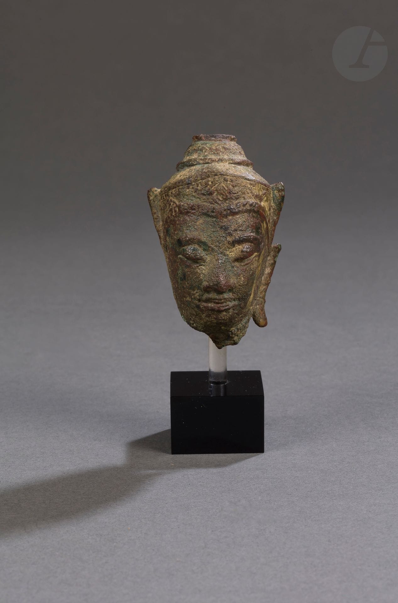 Small Buddha head in copper alloy with green patina, Thailand, 16th century
The face is oval and elongated, the lips well drawn, the eyebrows widely arched, the eyes half-closed and turned downwards, the earlobes elongated, the head surmounted by a crown worked in relief with geometric motifs, in the center of the skull the ushnisha protuberance is damaged, as well as an ear.
Height : 7 cm

