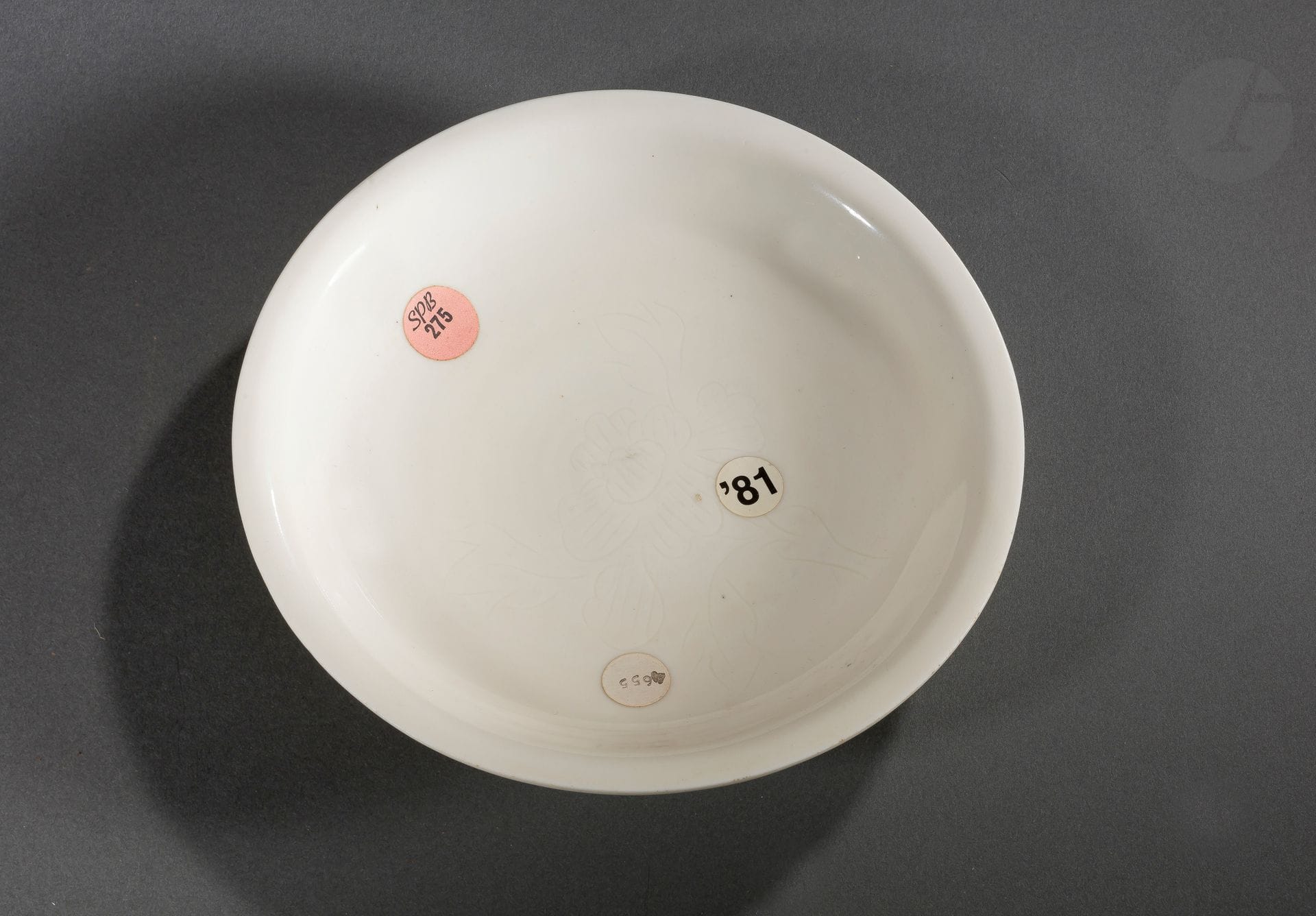 Coupe en porcelaine Blanc de Chine, Dehua, Chine, fin de la période Ming, XVIIe siècle
Légèrement creuse avec un bord évasé, le centre est incisé d’un décor de fleur de pivoine. L’intérieur, le revers de l’aile et le dessous sont recouverts d’une glaçure ivoire. Elle repose sur un talon non émaillé.
Diamètre : 22 cm

Porte des anciennes étiquettes de vente :
- SPB (Sotheby’s Parke Bernet) n°275.
- ‘81. 
- 4655.

Dehua, située sur la côte sud-est de la province de Fujian, est bien connue pour sa production de porcelaine blanche, connue des Européens sous le nom de « Blanc de Chine ». Les premières porcelaines de Dehua ont été produites dès le XIVe siècle, mais la production et la qualité de ces porcelaines ont atteint leur apogée aux XVIIe et XVIIIe siècles.

十七世纪 - 德化窑白釉刻牡丹 折沿盘

Collection particulière parisienne - lots de 78 à 127, 219 et 220
