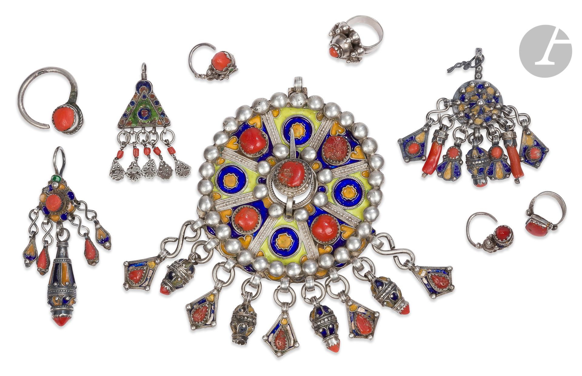 Tabzimt fibula, Algeria, Great Kabylie, Beni Yenni, 20th century
In silver with blue, yellow and apple green enamel decoration and coral cabochons, circular tabzimt fibula with pendants encircled with applied silver beads. Two rings, three earrings and three pendants in silver with coral cabochons, some enameled jewelry.
Diam. fibula: 10 cm; gross weight: 371 g
Some enamel jumps.

An Enameled Silver Tabzimt Fibula, Algeria, Great Kabylia, Beni Yenni, 20th century