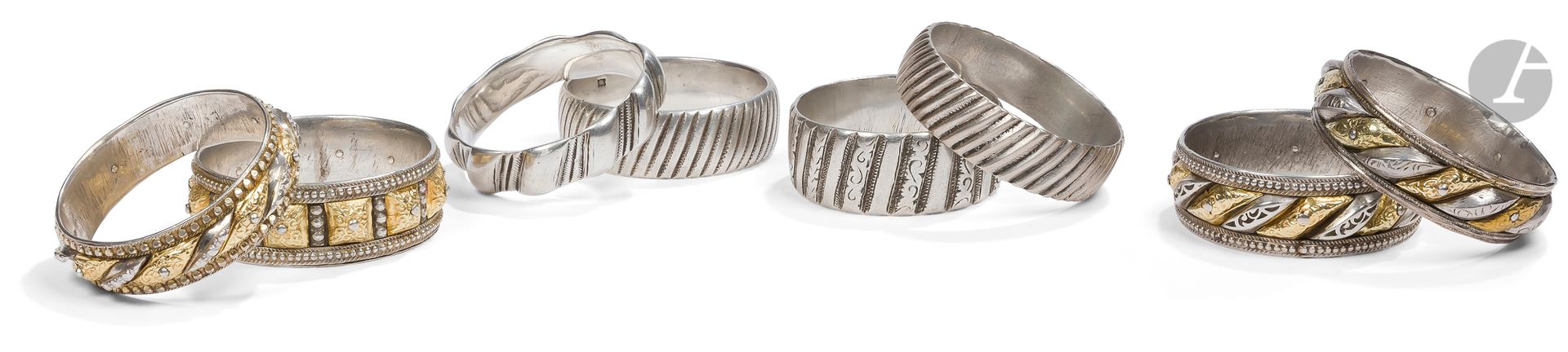 Huit bracelets godronnés dont quatre shams-u qamar, Nord du Maroc, XIXe - XXe siècle
En argent, quatre bracelets shams-u khamar (lune et soleil) partiellement dorés à godrons moulés et gravés d’un décor floral, trois soulignés de frises perlées, une paire à décor de stries obliques guillochées, les deux derniers à godrons lisses ou gravés d’un décor végétal alternant avec des lignes guillochées. 
Diamètre : 6,3 à 7 cm ; poids brut : 985 g

8 Knurled Silver Bracelets including 4 Shams-u Qamar, North Morocco, 19th - 20th century
