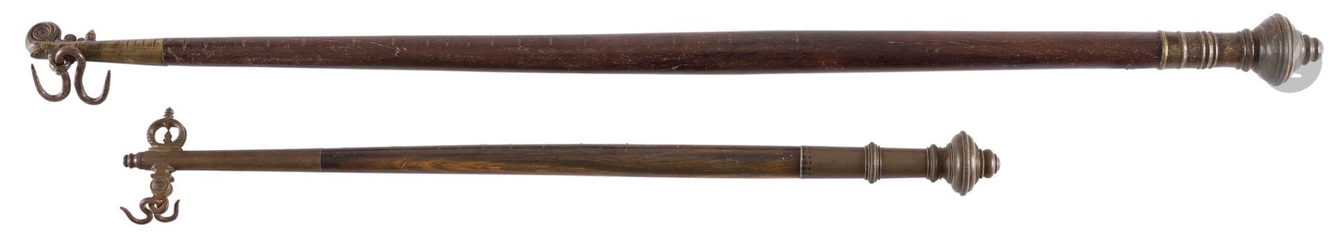 Deux pesons en bois et métal, Inde, Kerala, fin XIXe siècle
Fût cylindrique en bois gravé de stries pour le premier, incrusté de petits clous métalliques sur le second, à manche et extrémité en alliage cuivreux. Le manche marqué d’anneaux et achevé d’un bulbe, gravé d’une inscription sur le premier. Le crochet sinueux opposé à une tige métallique spiralée sur le premier, un anneau sur le second.  
Longueur : 84,5 et 56,5 cm
Usures

Two Portable Weighing Scales, India, Kerala, late 19th century