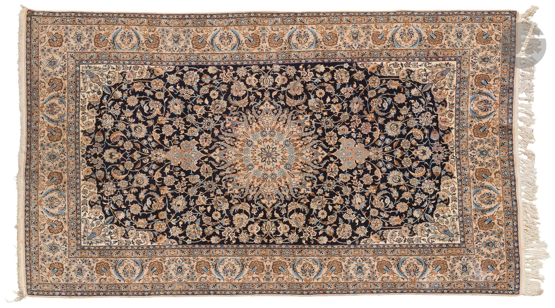 NAIN, XXe siècle, velours laine et soie (5%), chaînes et trames coton.
Tapis à médaillon central bleu et tabac sur fond bleu marine à rinceaux fleuris, bordure ivoire à guirlandes de fleurs. 
211 x 336 cm