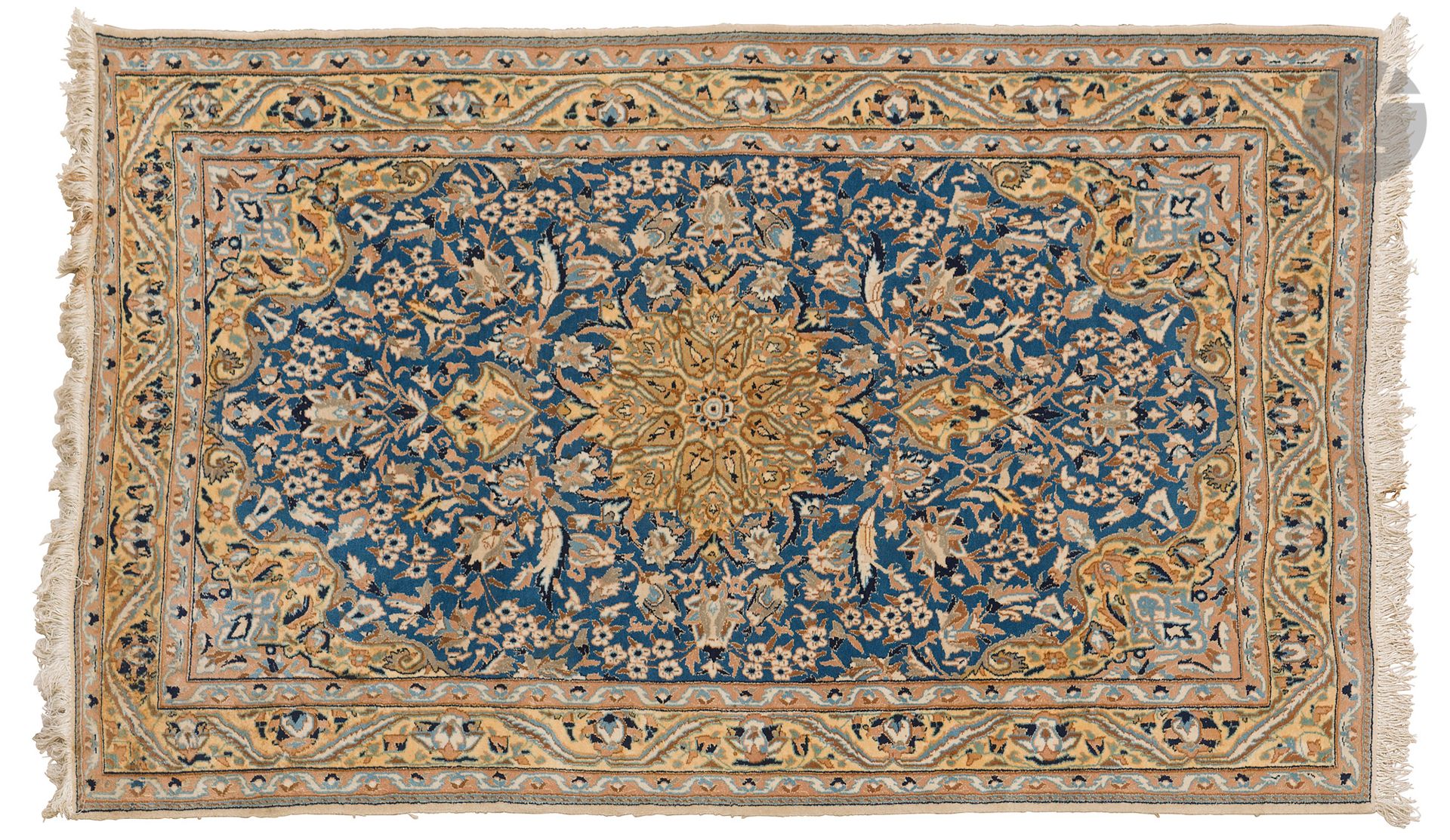 NAIN, XXe siècle, velours laine et soie (5%), chaînes et trames coton.
Tapis à décor d’un médaillon central tabac sur un fond bleu roi à rinceaux fleuris, bordure beige à guirlandes de fleurs. 
118 x 194 cm
