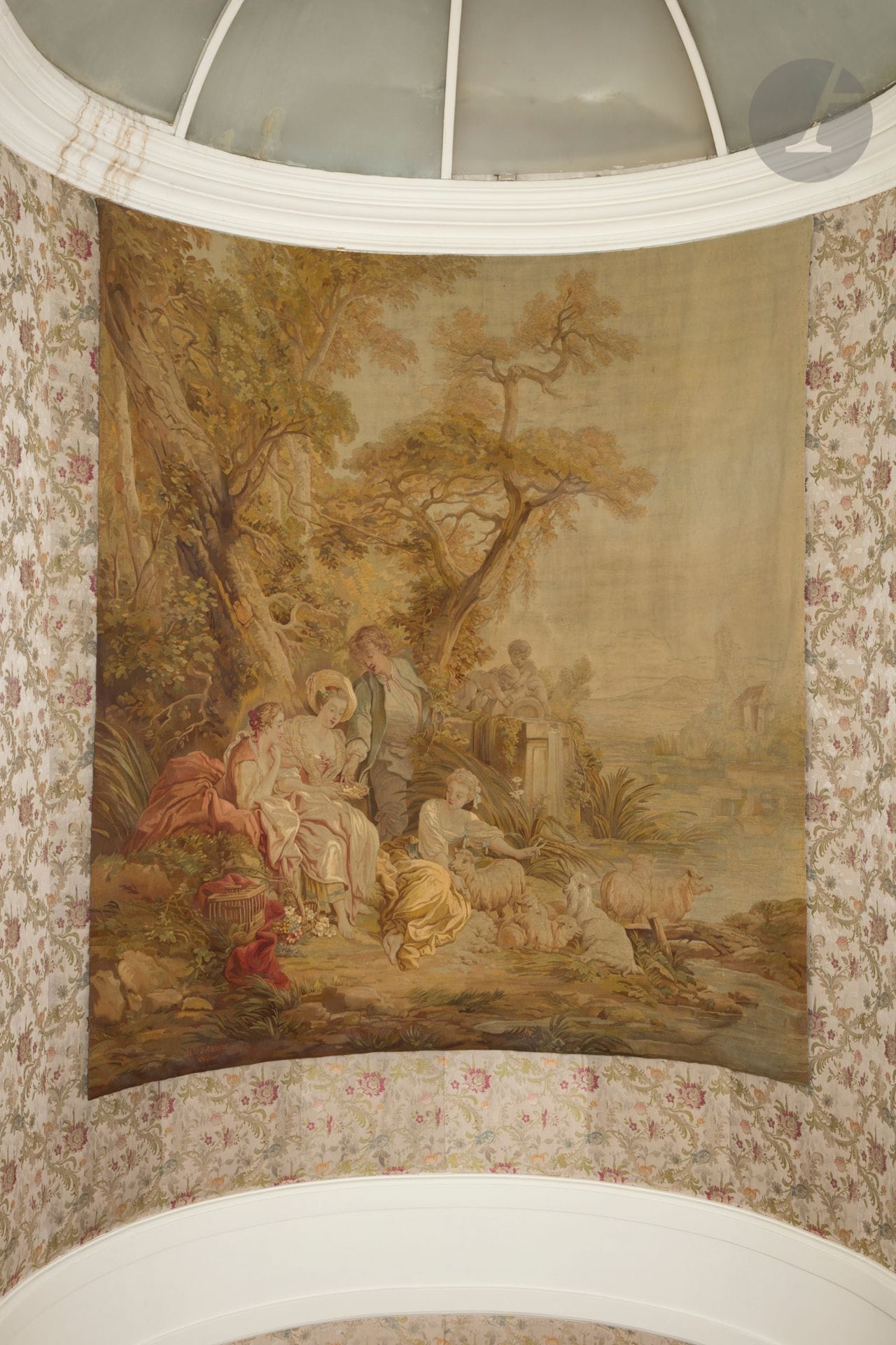 Très rare tapisserie tissée dans les ateliers Walmer à Neuilly-sur-Seine à décor d’une scène pastorale où l’on voit deux femmes discutant avec un jeune homme aux pieds duquel se trouve une bergère entourée de ses moutons sur un fond de forêt et d’une statue. 
Signée en bas à gauche MRD de Neuilly, et en dessous Walmer. 
Vers 1830.
230 x 235 cm