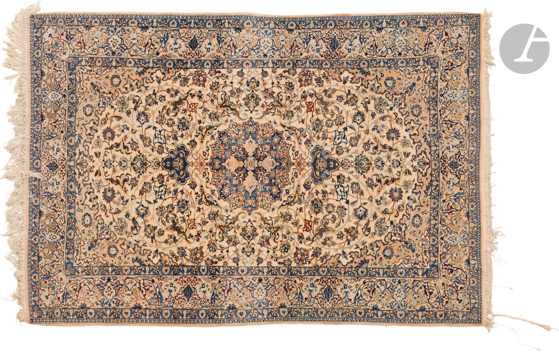 NAÏN, XXe siècle, velours laine, chaînes et trames coton.
Tapis en laine à médaillon central bleu sur un fond ivoire à rinceaux fleuris, bordure beige à décor de fleurs. 
225 x 160 cm