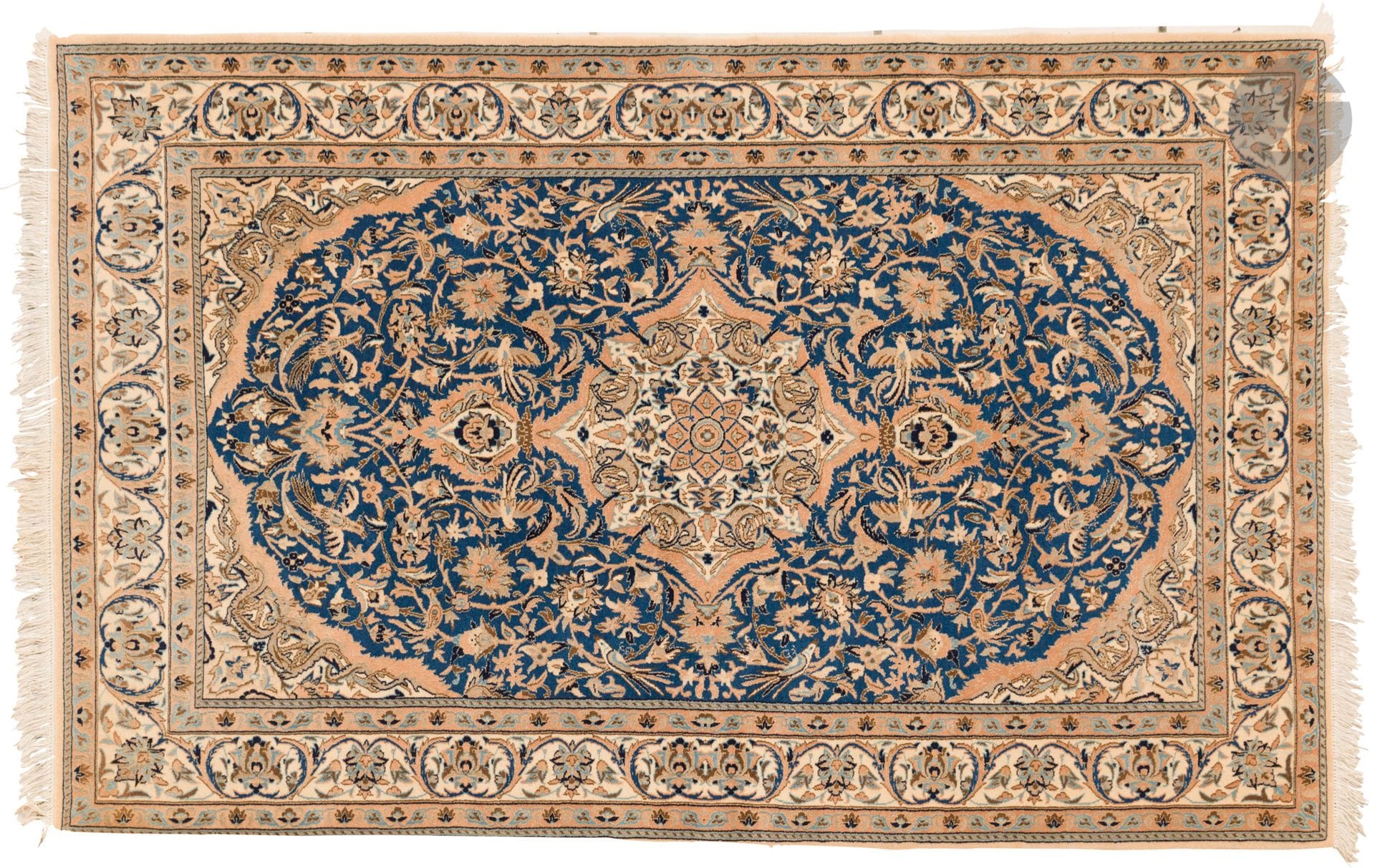 NAIN, XXth century, wool and silk velvet (5%), silk chains.
Carpet with a navy blue background decorated with a central rose window and floral scrolls, ivory border with garlands of flowers. 
118 x 183 cm