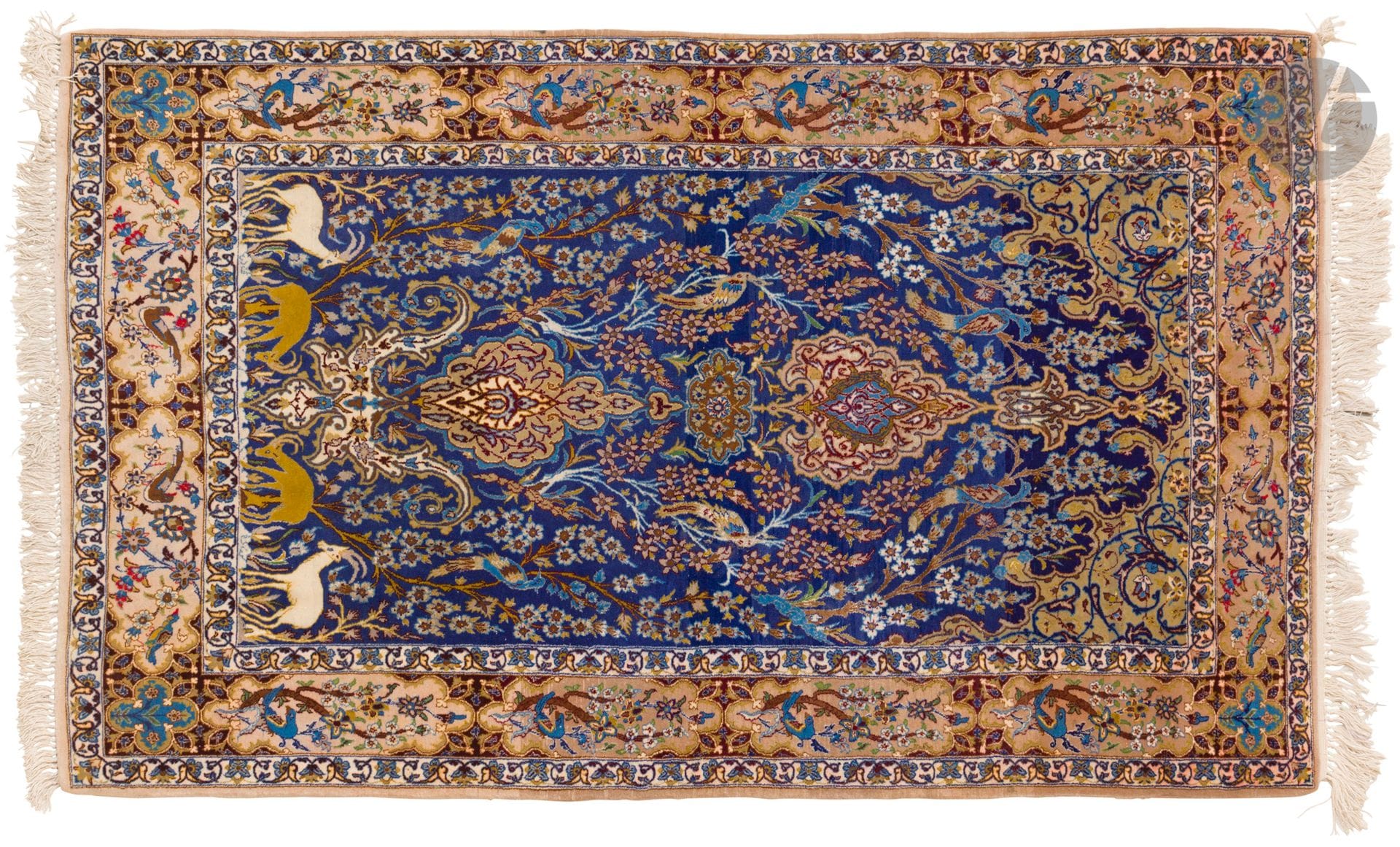 NAÏN, XXe siècle, velours laine, chaînes et trames coton.
Tapis à décor de volatiles et de gazelles sur fond bleu à arbustes fleuris, bordure rubis à cartouches décorées de volatiles sur fond rubis. 
108 x 169 cm
Coulé.