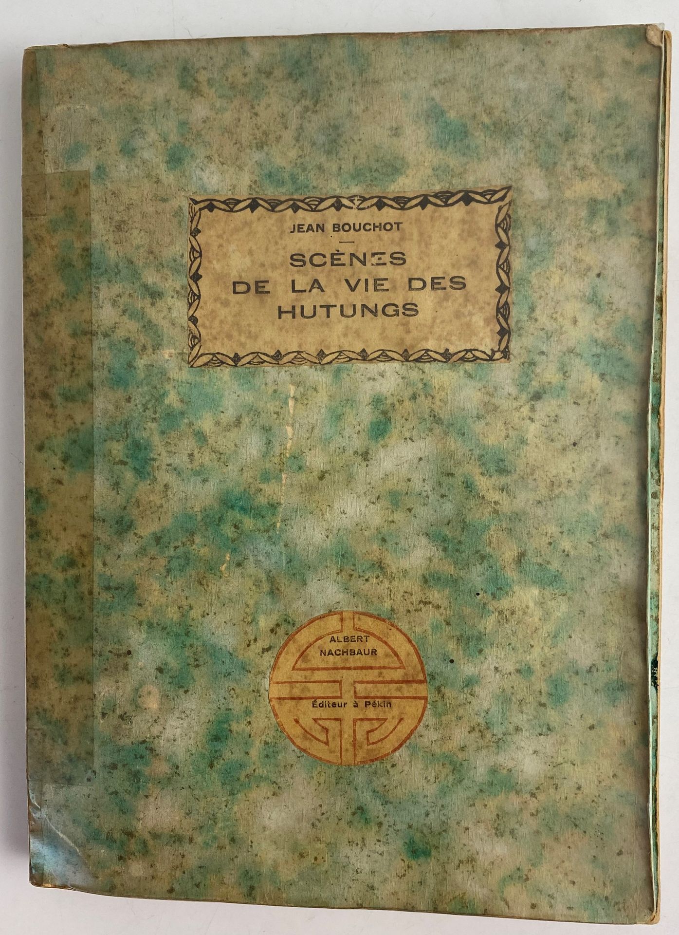 BOUCHOT (Jean).
Scènes de la vie des Hutungs. Croquis des mœurs pékinoises. Préface d'Albert Nachbaur Directeur du Journal de Pékin.
Pékin : Albert Nachbaur, 1926. — In-8, broché, deux étiquettes imprimées collées sur le premier plat de couverture.

Troisième édition rare de l'un des livres les plus pittoresques édités sur la Chine et les chinois.

Il est l'œuvre de l'archiviste et paléographe Jean Bouchot (1886-1932) qui, fort de son séjour de trois ans à Pékin dans les années 1920, dresse un portrait des plus instructifs et amusants de cette ville et de ses hutungs. Ce terme est défini ainsi dans l'introduction : « Méandre et labyrinthe, ruisseaux fangeux, trous à purin, pavée d'immondices et bitumée de crotte, telle est la hutung pékinoise » (p. b).

Ainsi Bouchot nous dépeint la vie populaire chinoise à l'époque, telle qu'il l'a vue, « avec autant de précision, de sureté, d'exactitude, d'observation, dans une langue impeccable, élégante et riche » (p. c).

L'édition est illustrée de nombreux croquis en rouge hors et dans le texte, ainsi que de deux grandes planches dépliantes en couleurs représentant respectivement la procession d'un mariage chinois et celle d'un enterrement.

Couverture réparée à l'aide de scotch. Déchirure sans manque, restaurée, à la seconde planche dépliante. Quelques salissures à l'intérieur.