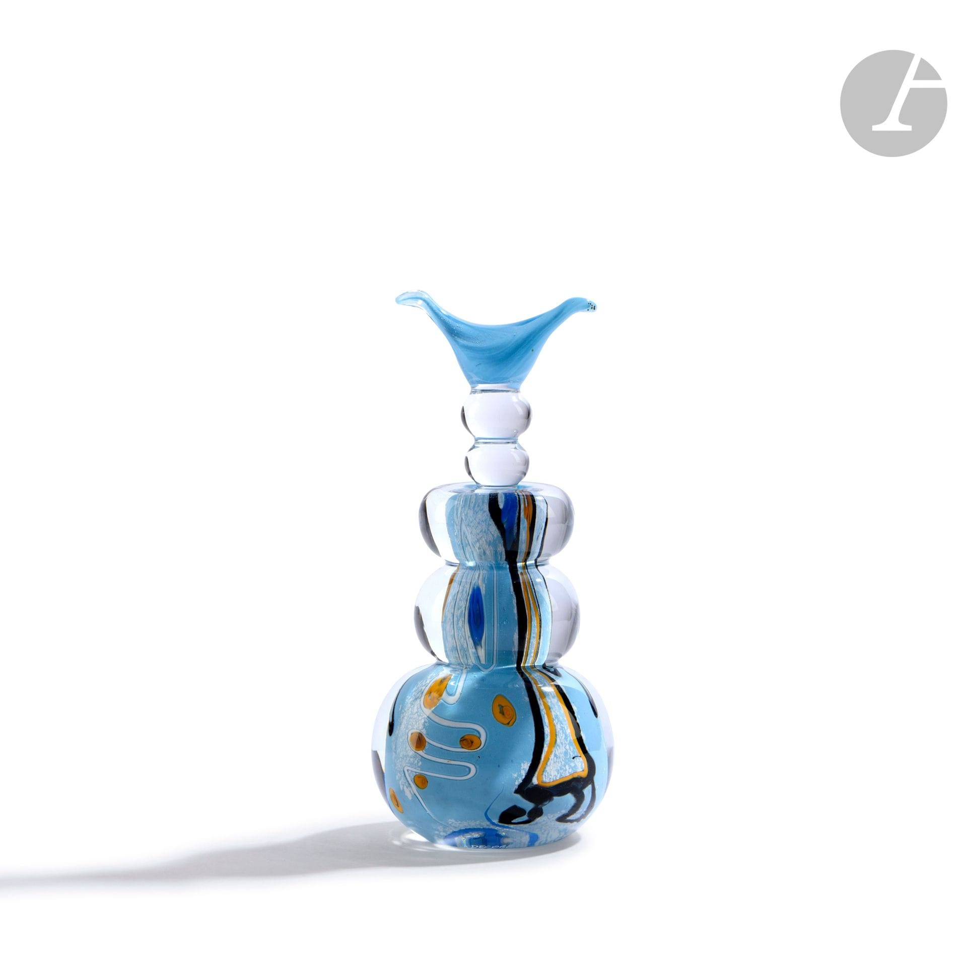 Élisabeth DECOBERT et Francis BÉGOU (France, XXe siècle)
Flacon en verre soufflé en forme d’anneaux, à décor abstrait polychrome sur fond bleu ciel, et son bouchon à cornes. Signé et daté 1993 à la base. H. 17 cm – D. 7 cm