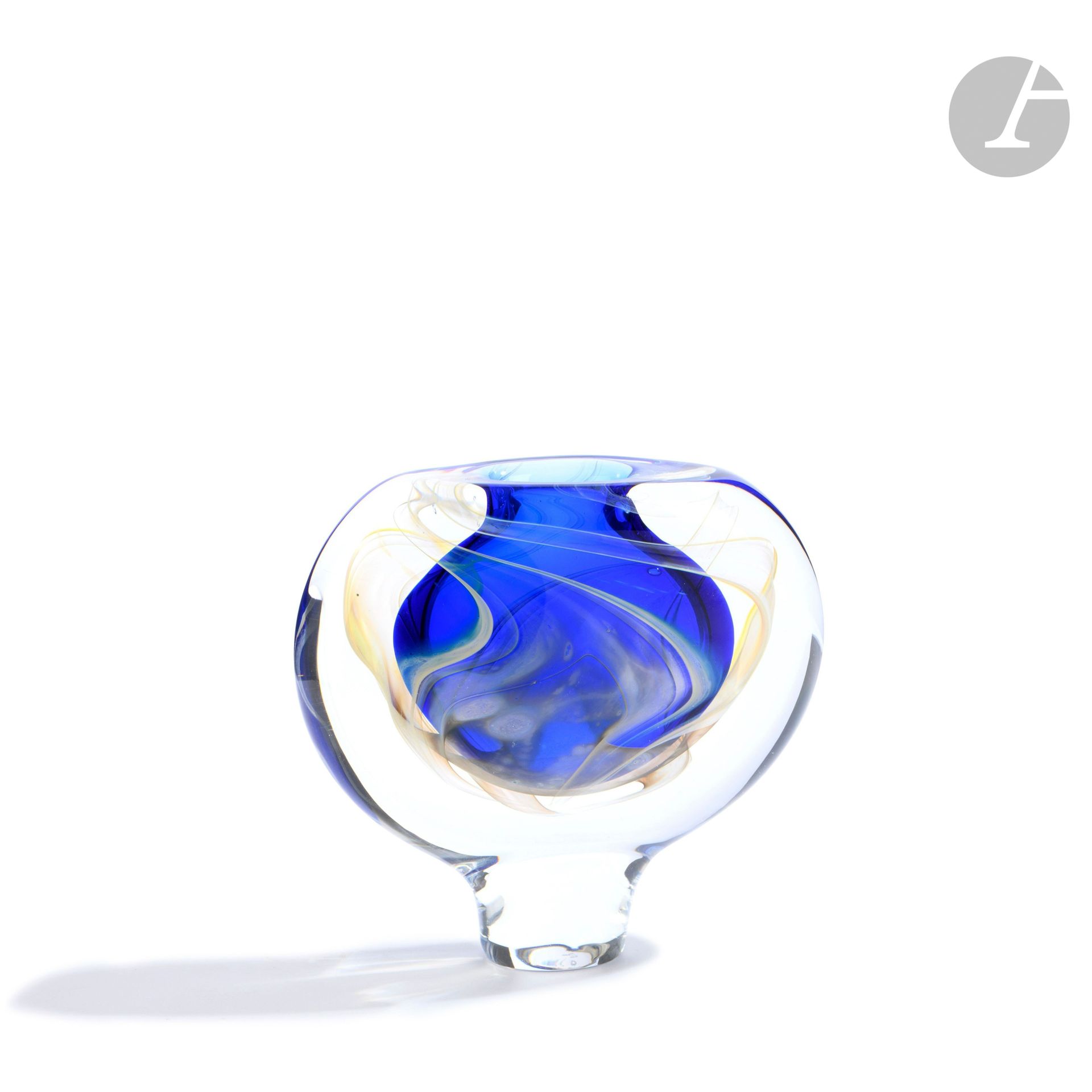 Éric LAURENT (France, 1959-2018)
Blown glass vase on foot, decorated with gray ribbons on a blue background. Signed, dated (19)89, located in Allex and numbered J52 under the base. H. 12 cm - W. 12 cm - D. 4 cm