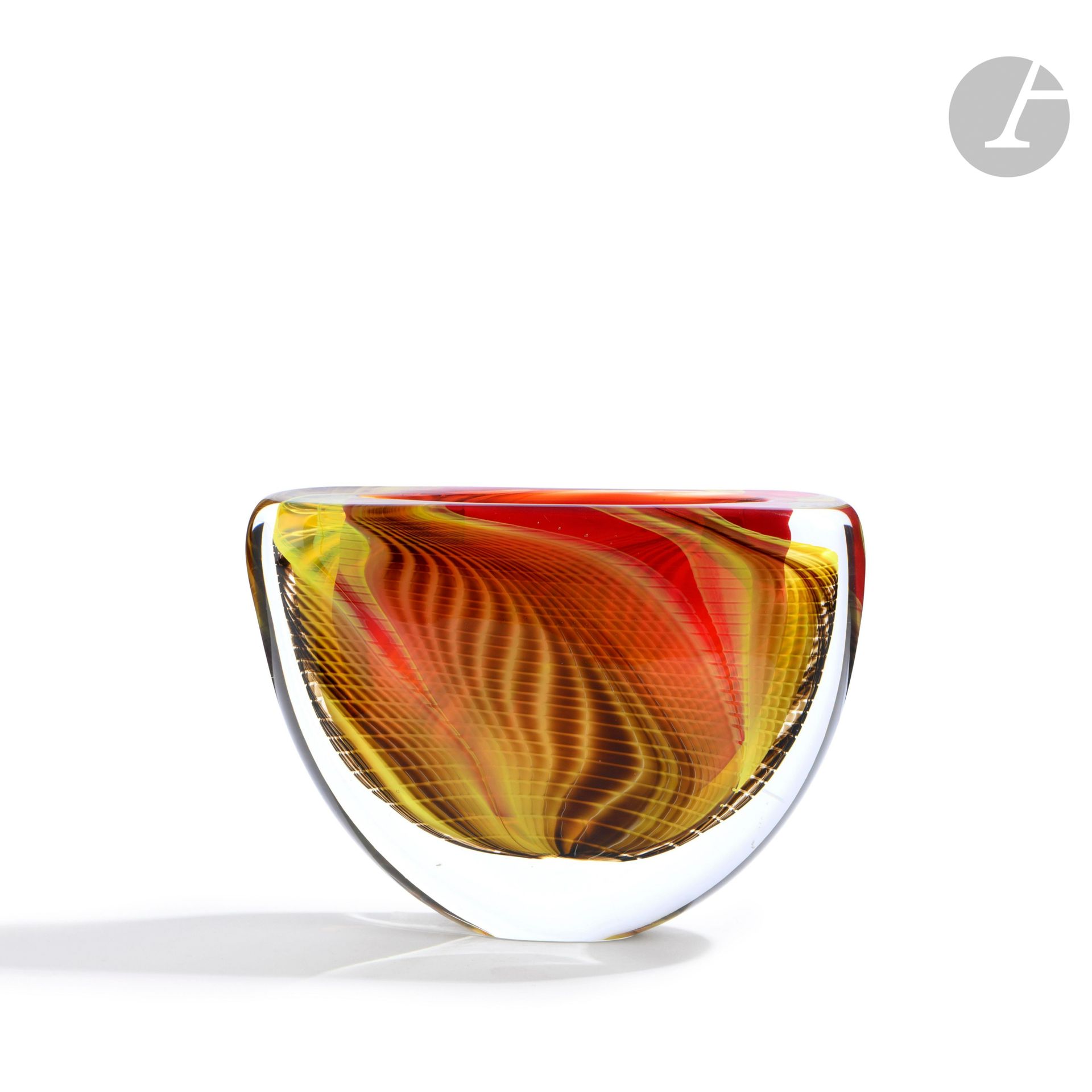 Hervé RASPAIL (France, né en 1960)
Vase en verre soufflé de forme aplatie, à décor quadrillé de flammes jaune, orange et rouge. Signé, numéroté 1H87 et daté (19)89, situé à Allex sous la base. H. 15 cm - L. 20 cm - P. 5 cm