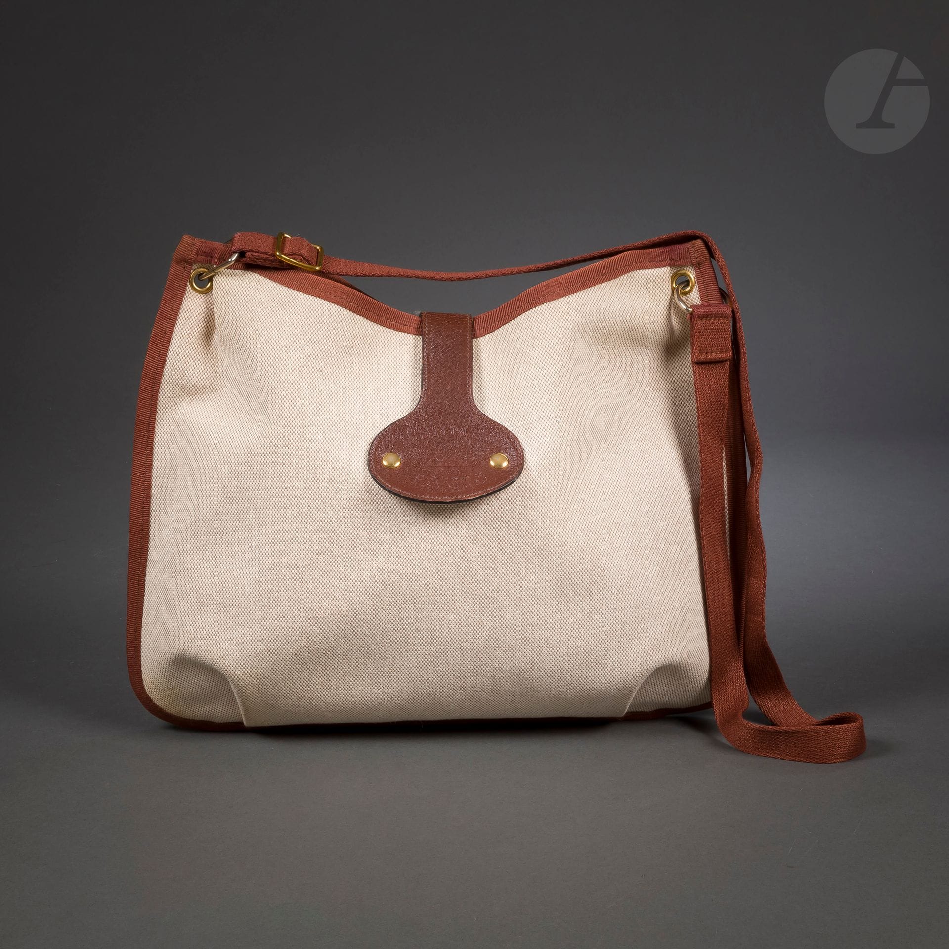HERMES Paris Made in France
Sac bandoulière en toile beige et marron, attache en cuir marron à pressions, housse
40 x 30 cm