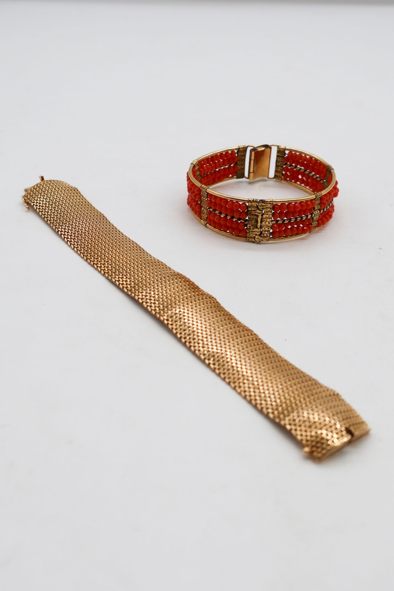 Bracelet souple en or 18K (750) tressé. Travail français. Longueur : 19,7 cm environ. Poids brut : 67 g (déformations ; on joint un bracelet ouvrant en métal doré orné de quatre lignes de billes de corail)
