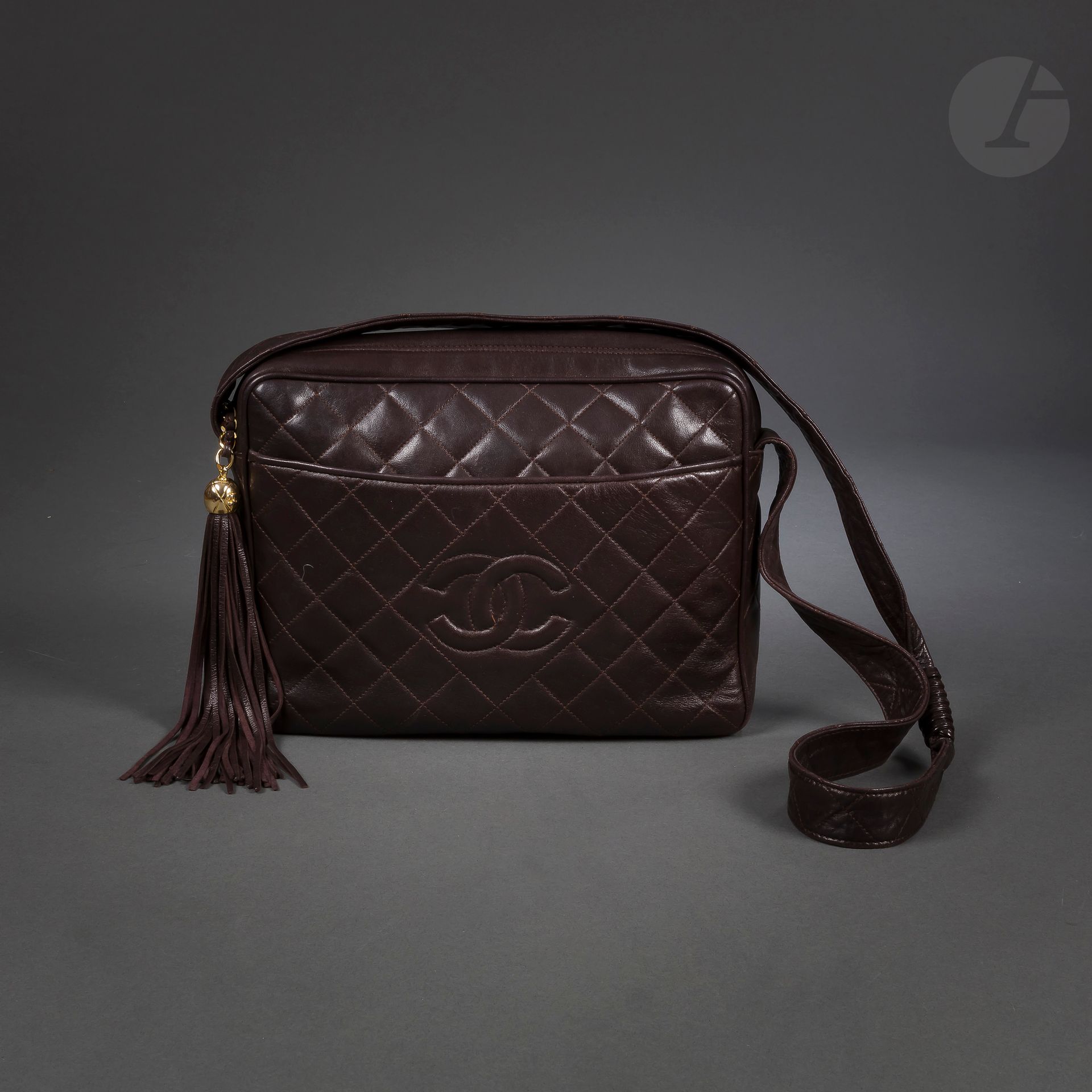 CHANEL Made in France
Sac bandoulière Caméra en agneau marron surpiqué, avec son pompon à lanières de cuir
27,5 x 20,5 x 7,5 cm (très légères usures aux angles, tache dans la poche intérieure)