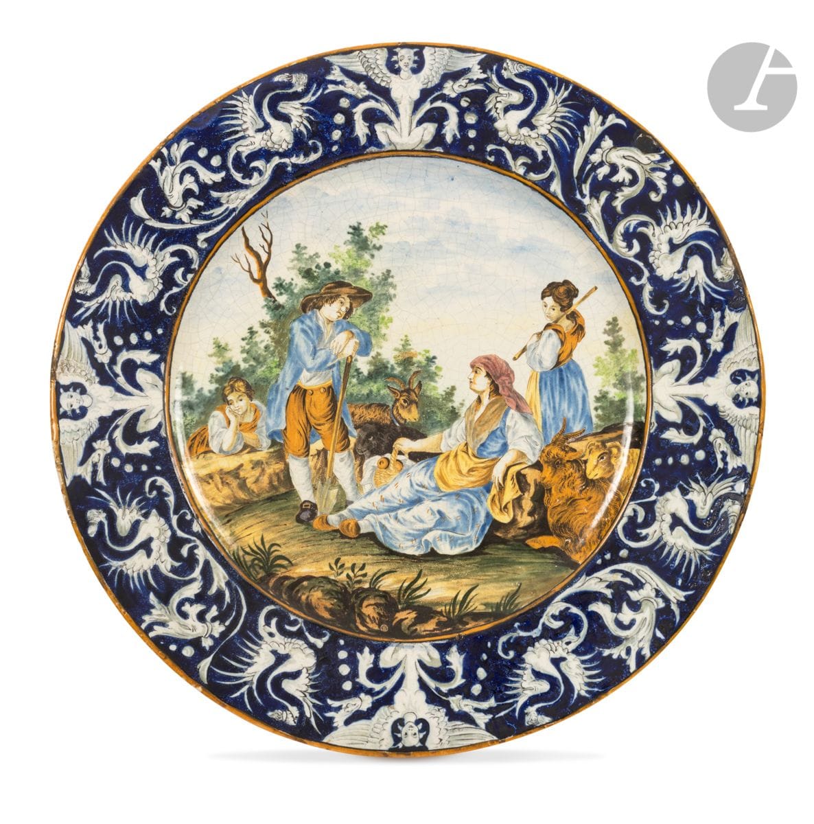 ITALY XIXth century
Large round dish in majolica with central polychrome decoration of a group of shepherds and their flock. The wing decorated with grotesques on a blue background.
Diam. 61 cm
Dish veiled, some defects of cooking and small chips.