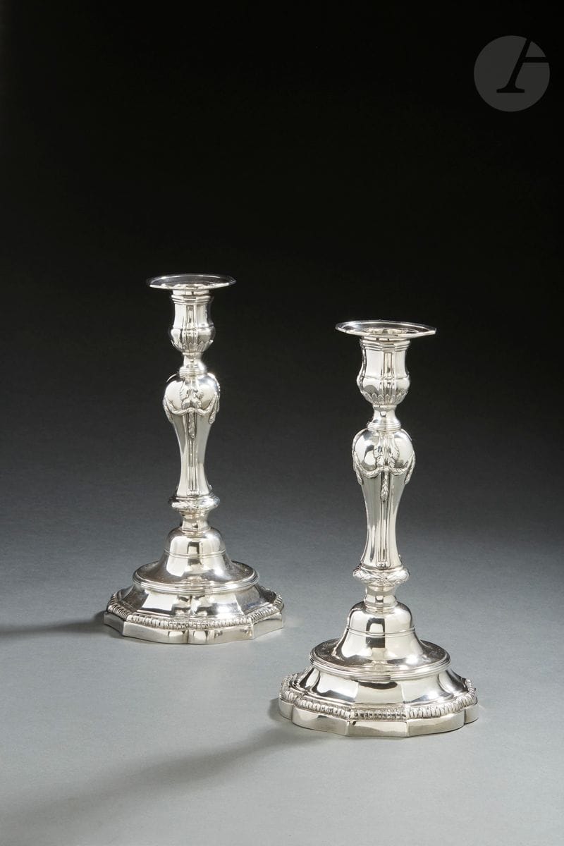 LILLE 1782 - 1783
Paire de flambeaux en argent et leurs bobèches. La base à neuf contours est repoussée d’un rang de feuilles sur fond amati en rappel sur le binet à contours. La cuvette est bordée de rangs de filets en rappel sur la collerette. La doucine reprend le motif à pans de la base. Le fût balustre à côtes et pans part d’un nœud de lauriers enrubanné. La partie haute est agrémentée d’une guirlande de feuilles en chute. Les bobèches portent le petit poinçon de maître orfèvre.
Maître orfèvre : François- Joseph BAUDOUX, reçu en 1738
Poids : 1353 g - hauteur : 27 cm - diamètre de la base : 14,2 cm

Littérature :
Reproduit et décrit dans l’ouvrage de Madame Nicole Cartier, Les orfèvres de Lille, Tome II, page 684, sous le numéro 349