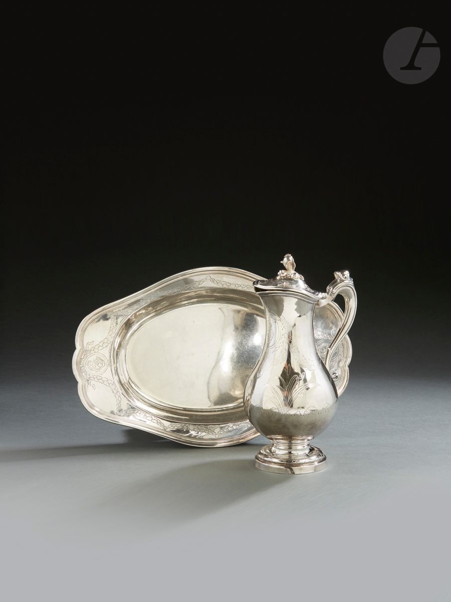 MARSEILLE 1784
Aiguière et son bassin en argent. Le bassin, de forme ovale, bordé de filets, le marli gravé d’une guirlande agrémentée aux extrémités d’un ruban maintenant un médaillon gravé d’initiales entrelacées. L’aiguière, de forme balustre, pose sur un piédouche gravé de feuilles en rappel à la base de l’aiguière, le corps est rehaussé de roseaux et de guirlandes reprenant le décor du bassin, en rappel sur le couvercle à charnière terminé par une graine et son feuillage en applique. L’anse à enroulement est surmontée d’un escargot d’eau douce.
Maître orfèvre : attribués à J. ALLIES, reçu en 1775
Poids : bassin : 733 g - longueur : 38,2 cm - largeur :  24,6 cm, aiguière : 858 g - hauteur : 27,5 cm