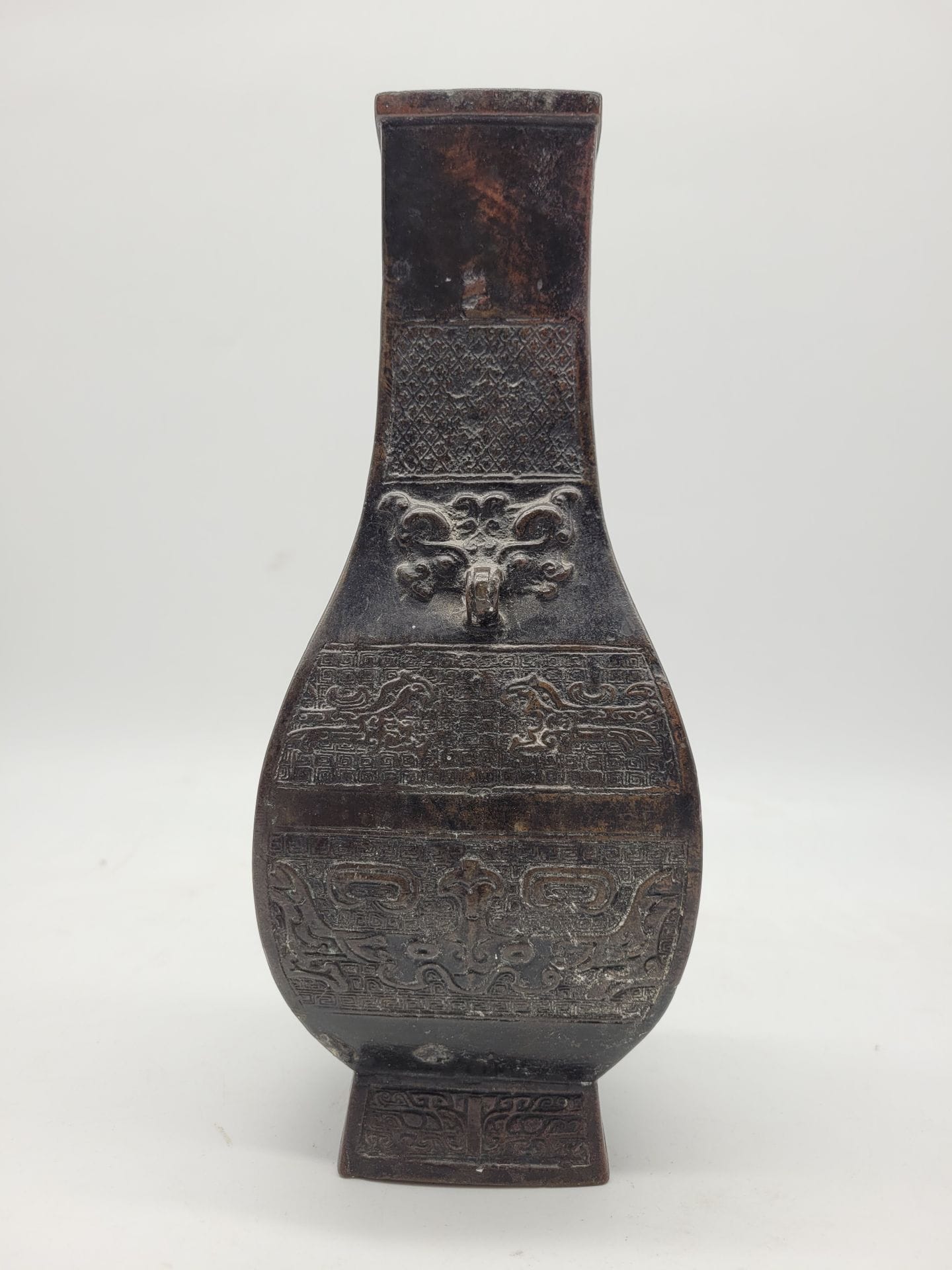 Vase archaïsant de forme fanghu en alliage cuivreux, Chine 
Panse à décor de masques de taotie et de kui, deux anses en forme de masques de taotie. 
Hauteur : 25,7 cm 
Petits défauts.