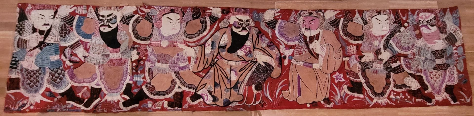 Large embroidery of a theater scene, Japan
On a red background and polychrome silk threads representing seven characters. 
Size : 73 x 315 cm 
Accidents, missing and patches on the back.