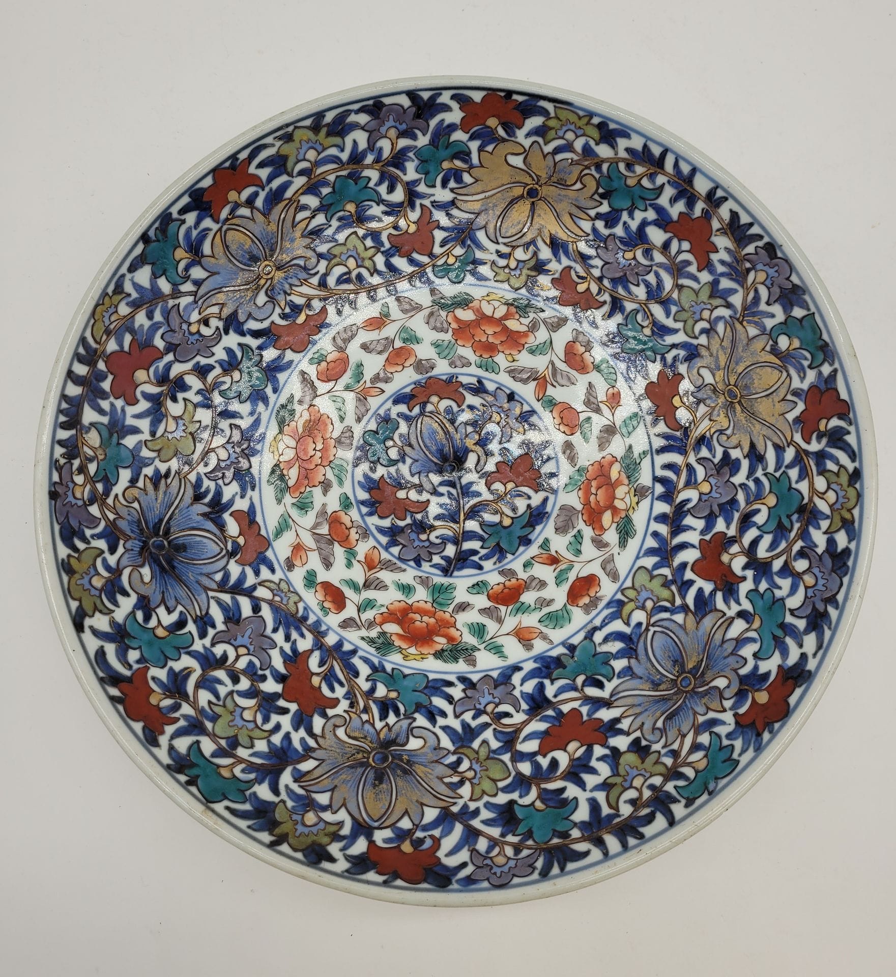 Plat en porcelaine, Japon, fin XIXe - début XXe siècle 
A décor végétal en bleu sous couverte, rehaussé d'émaux polychromes. 
Diamètre : 31 cm