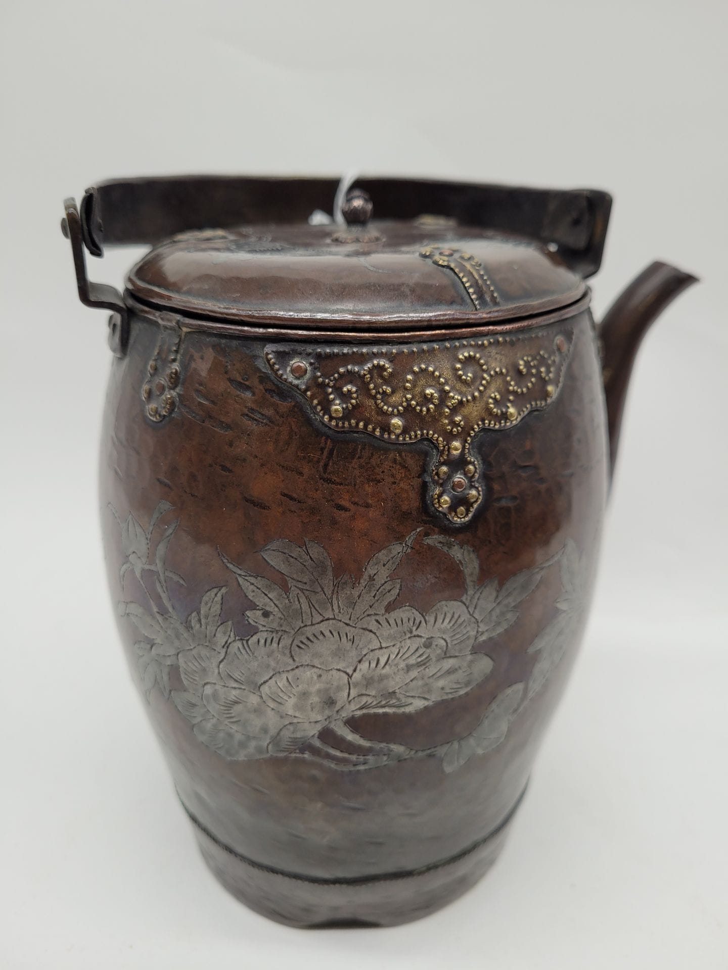 Verseuse en cuivre à patine brune, Chine ou Japon, vers 1900 
A décor de fleurs, garnitures en laiton et bourgeon formant la prise du couvercle. Marque sous la base. 
Hauteur : 16 cm 
Petit enfoncement