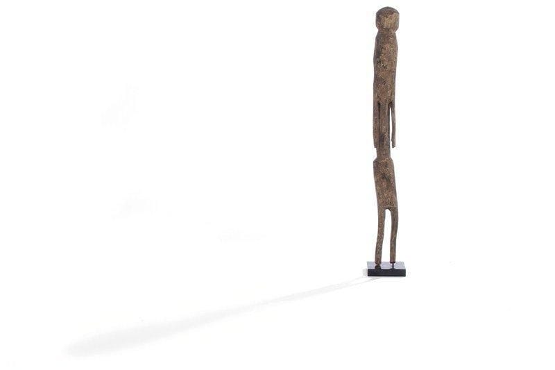 Statue MOBA (Togo). De forme longiligne, le torse et le bassin très allongés, les bras courts le long du corps. Tête cubique sans bouche, nez et yeux. Patine brun clair. H : 73 cm.