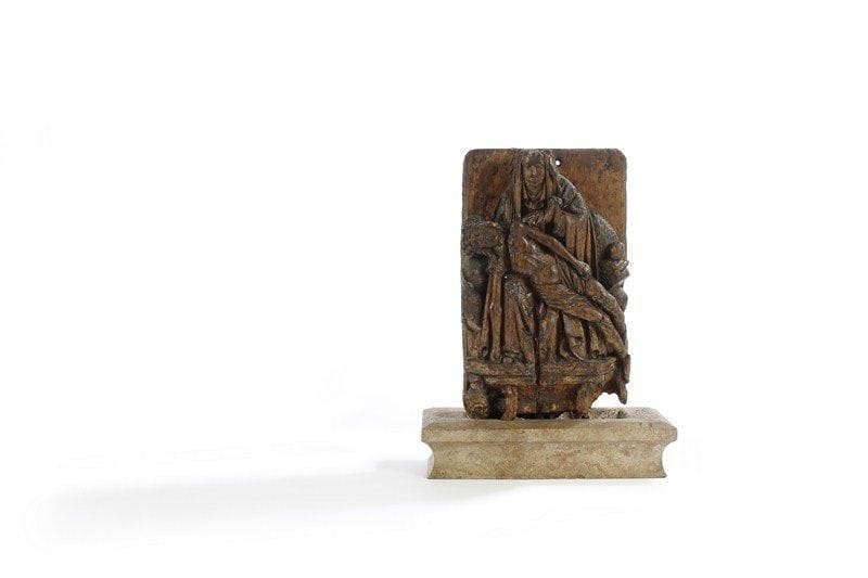 Piéta en bois sculpté en très haut relief de la fin du XVe siècle. La Vierge est assise en prière devant un fond uni tenant le Christ mort sur ses genoux, ses vêtements portent de nombreux plis cassés, à bec et à enroulement typiques du XVe siècle, elle repose en basse sur un chapiteau à pans coupés orné d'une tête de monstre. Nombreux accidents et manques en différents endroits. Elle est présentée sur un socle en pierre postérieur. H : 58 cm.