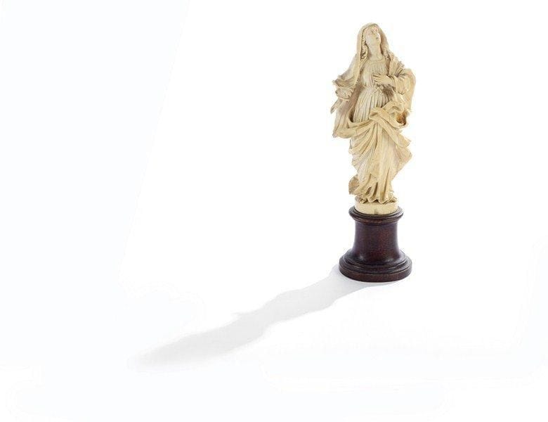 Sainte Magdeleine en ivoire sculpté, la tête inclinée vers le haut, bras droit sur la poitrine, tunique plissée devant. Ecole allemande de la fin du XVIIe siècle. Socle en bois tourné. Petits manques. H : 17,5 cm.