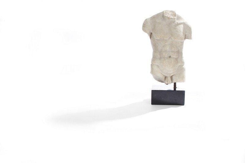 Torse d'homme en marbre blanc sur un socle en pierre noire. Manques. H : 74 cm.