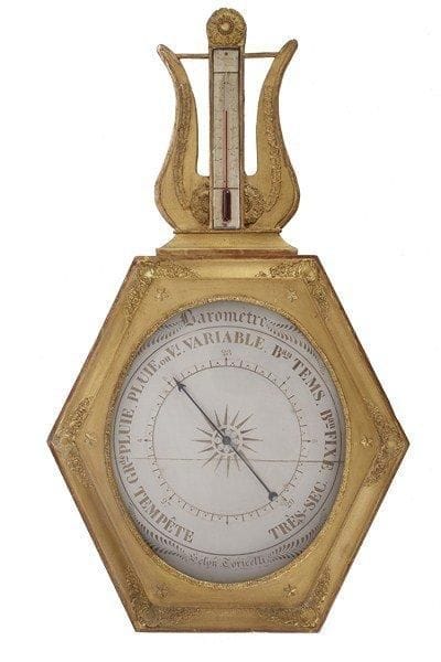 Baromètre-thermomètre en bois mouluré et stuc dorés, le baromètre de forme hexagonale est surmonté du thermomètre inscrit dans une lyre. Epoque Restauration. Petits accidents, manque un tube. H : 84 cm - L : 48 cm.