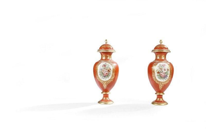 Importante paire de potiches  couvertes, en porcelaine à fond rouge tomate, à décor dans des réserves de branchages fleuris et feuillagés, à encadrement de rinceaux dorés. Couvercles à prise en forme de graine. Bases à piédouche. XIXe siècle. Usures et éclats. H : 81 cm - D : 28 cm.