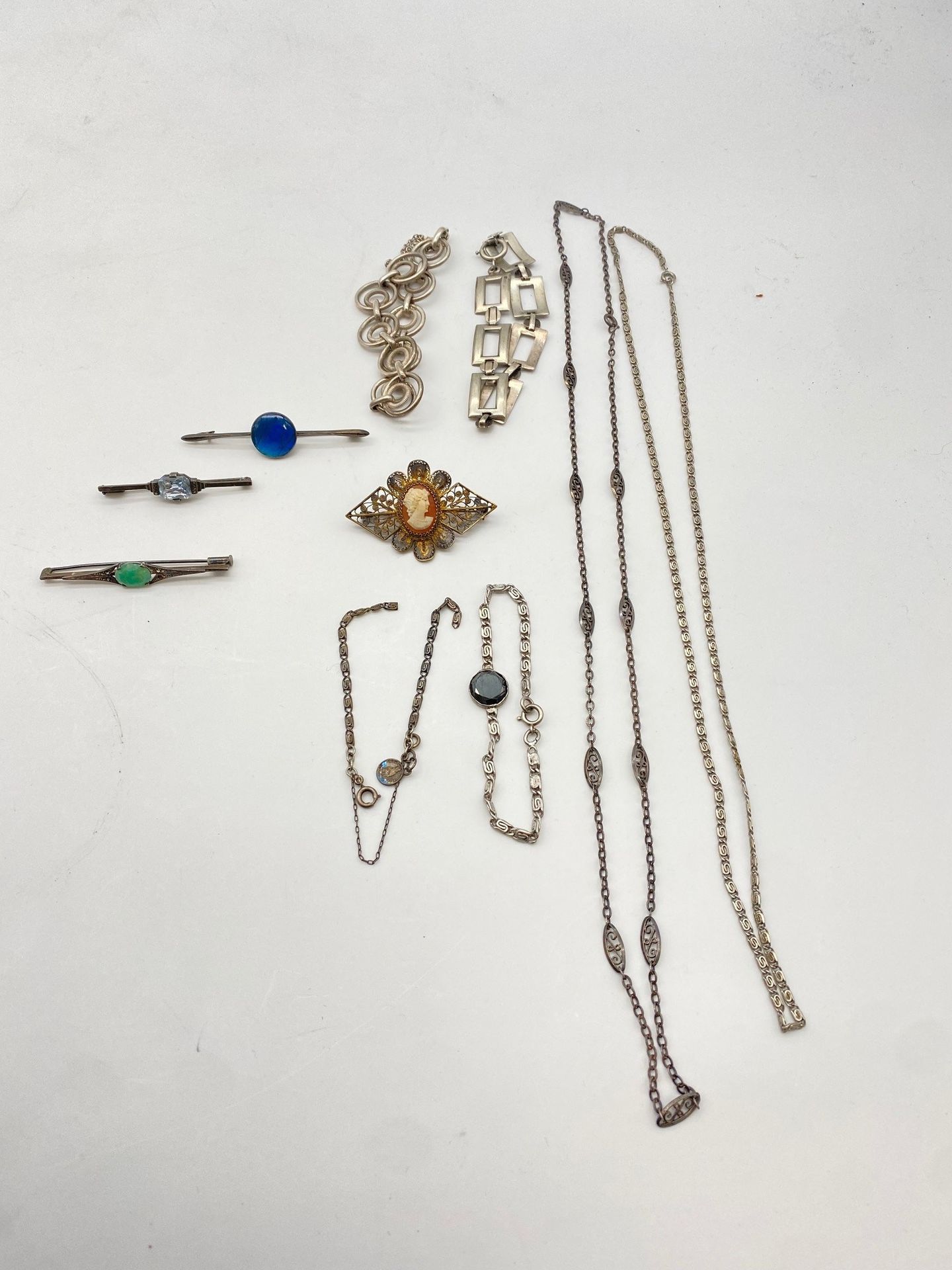 Lot de bijoux en argent. Poids brut : 85 g

- 3 bracelets, 1 chaine de montre (68cm), une chaine (60cm) et bris. Poids brut: 66,6 g

- 4 broches dont 3 "barrettes", avec motifs centraux. Poids brut: 18,5 g