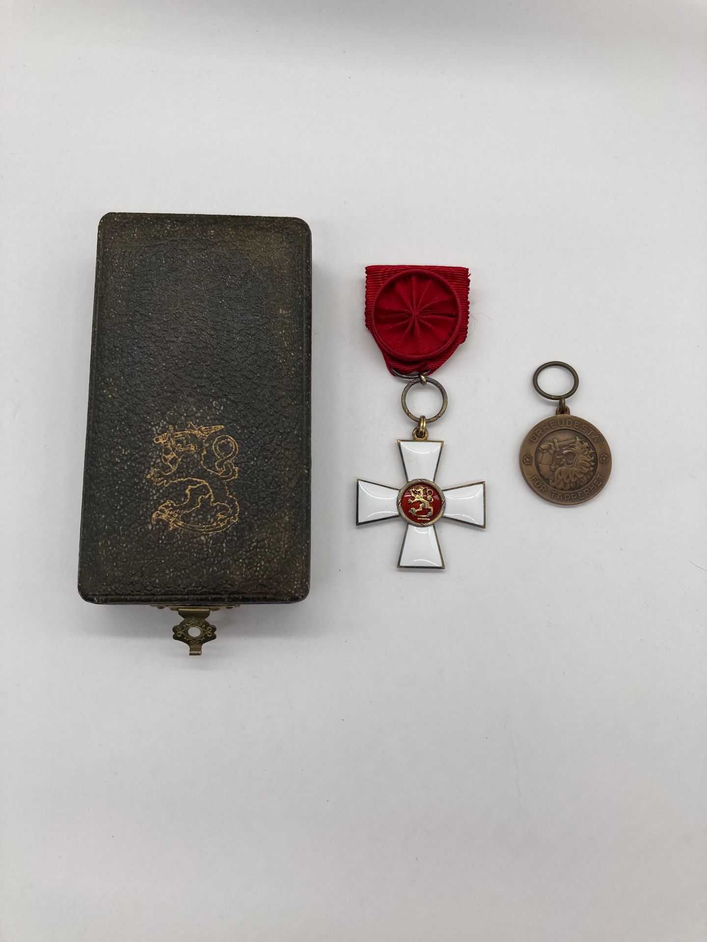 FINLANDE 
ORDRE DU LION. 
Étoile d’officier. 
En vermeil et émail. Centre en plusieurs parties. Restes de poinçon de titre. Court ruban à rosette et agrafe. 
39 mm - Poids brut : 20 g 
Dans son écrin au Lion finlandais, de la Maison TILLANDER. 
T.T.B. à SUP. 
On y joint une médaille de la Bravoure de 2e classe en bronze (1918).