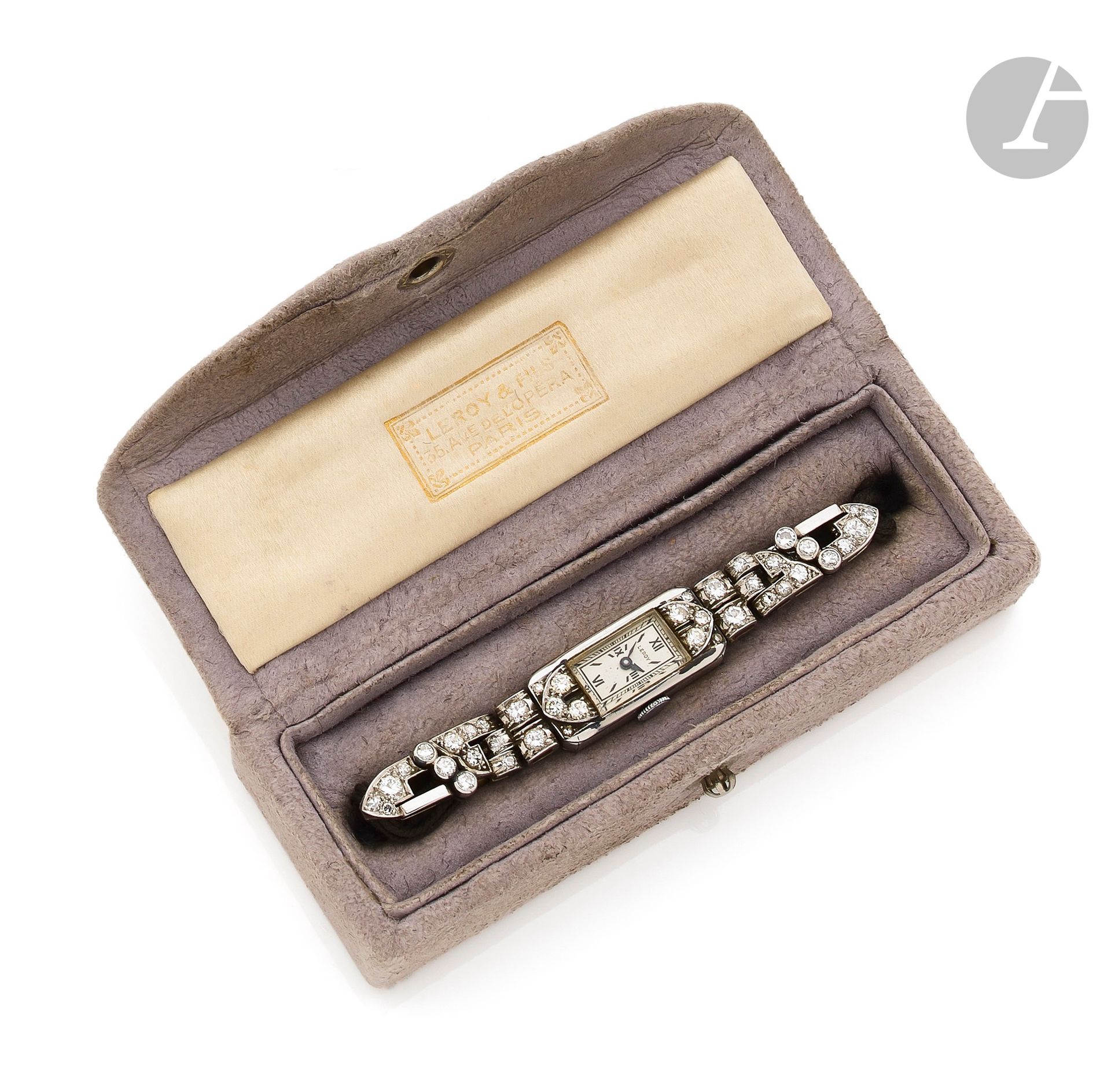 LEROY & FILS
Années 20
Montre bracelet de dame en platine et diamants sur cordon d’époque Art Déco. Boîtier : rectangulaire en platine et attaches articulées, à motif asymétrique, serties de diamants.
Signée à l’extérieur Leroy & Fils, 35, av. Opera.
Cadran : argenté avec index et chemin de fer peints. Mouvement : mécanique, non signé. Bracelet cordon avec une boucle simple.
Cadran et boîtier signés.
Numérotée 156124.
Dim. : 23 x 10 mm
Poids brut : 18,7 g
Avec son écrin d’origine signé Leroy & Fils, 35, av. Opéra, Paris.