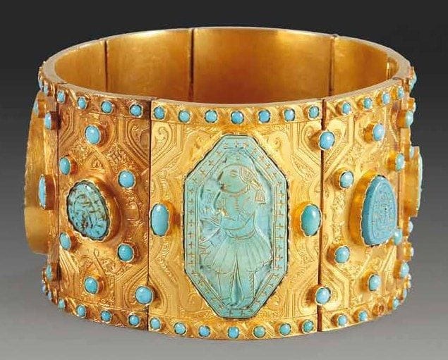 BRACELET QÂJÂR EN OR AUX FIROUZEH, IRAN, XIXE SIÈCLE Large bracelet articulé au décor gravé d'un ruban recti-curviligne dessinant des cartouches sur fond de rinceaux. Chaque partie est sertie de cabochons turquoise de différentes dimensions: trois grands gravés et dorés de personnages à l'européenne et cinq plus petits inscrits en persan. En bordure, cordon perlé de petites turquoises ainsi qu'en semis entre les grands cabochons. Poids brut: 114 gr. Ces turquoises de différentes tailles, dites firouzeh, sont gravées de souhaits et injonctions, ainsi que de personnages. Elles étaient certainement utilisées comme billets et cadeaux, avant d'être remontées dans des bijoux comme dans le cas présent