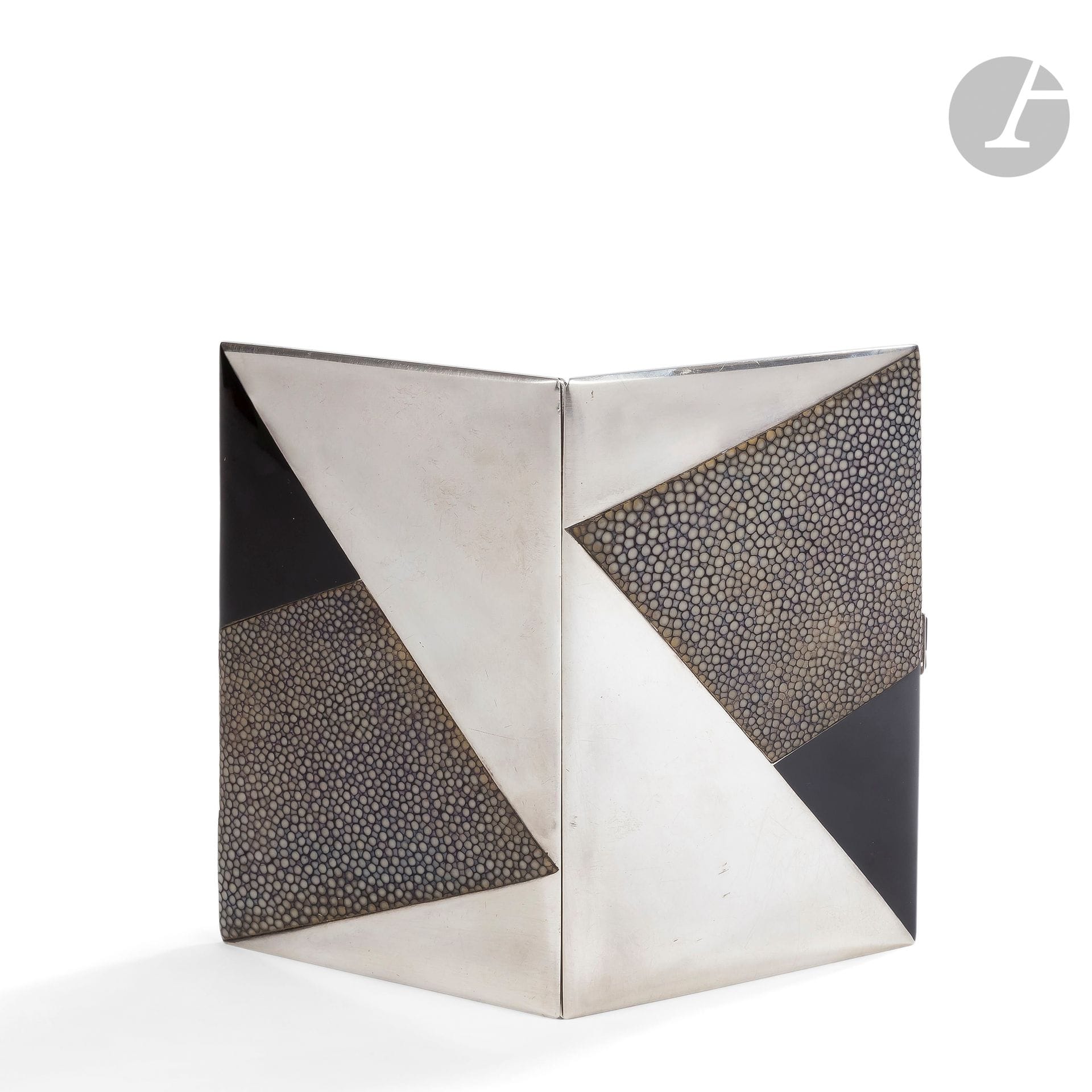 RAYMOND TEMPLIER (1891-1968) – MEMBRE DU GROUPE DES CINQ (CHAREAU – DOMINIQUE – LEGRAIN - PUIFORCAT – TEMPLIER)
Triangles, légère variante du modèle présenté au Salon d’Automne, Paris, 1927
Rare et exceptionnel étui à cigarettes en argent, laque et galuchat.
Chaque face présentant le motif titre réalisé, d’une part, en laque noire et, d’autre part, en parement de galuchat rehaussé de noir sur fond argent.
Le bouton-pressoir en onyx.
L’intérieur en vermeil.
Présenté dans son écrin d’origine siglé à l’or Raymond TEMPLIER – Paul TEMPLIER et Fils – Joaillers Fabricants – 3 place des Victoires Paris – à l’intérieur du couvercle.
Vers 1927-29.
Une petite fracture au bouton-pressoir.
Signé Raymond TEMPLIER à l’intérieur et porte à deux reprises (sur chaque face intérieure) les poinçons du Maître-Orfèvre Jean Trotain (écrit parfois par erreur Trottin), orfèvre exécutant pour Raymond TEMPLIER, et de garantie.
Longueur : 13 cm – Largeur : 8,5 cm
Poids brut : 172,2 g

Bibliographie et œuvres en rapport :
- L’Art Vivant – N° 70 du 15 novembre 1927. Un étui à cigarettes, au décor très proche de notre œuvre et réalisé en laque et peau de lézard présenté au Salon d’Automne de 1927, reproduit page 925.
- Laurence Mouillefarine, Véronique Ristelhueber – Raymond Templier - Le bijou moderne – Éditions Norma, Paris, 2005. Dés étuis à cigarettes très proches de notre œuvre reproduits page 220, 221, 224 et 227.