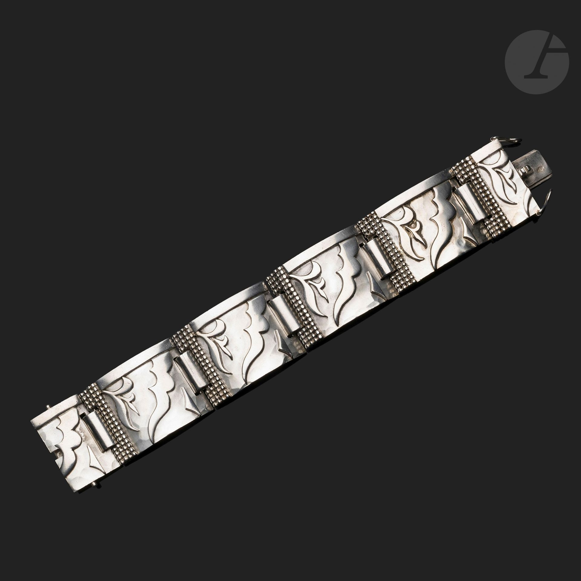 JEAN DESPRÉS (1889-1980)
Modernist bracelet with five convex articulated plates, one of which is in two parts.
Decorated with applications of free-form motifs, barrettes and quadruple rows of pearls on a broad hammered background.
It bears the Master Goldsmith hallmark twice, once on the clasp and once on the back of a plate, and the title hallmark twice on the clasp.
Length : 19.5 cm
Weight: 170.65 g