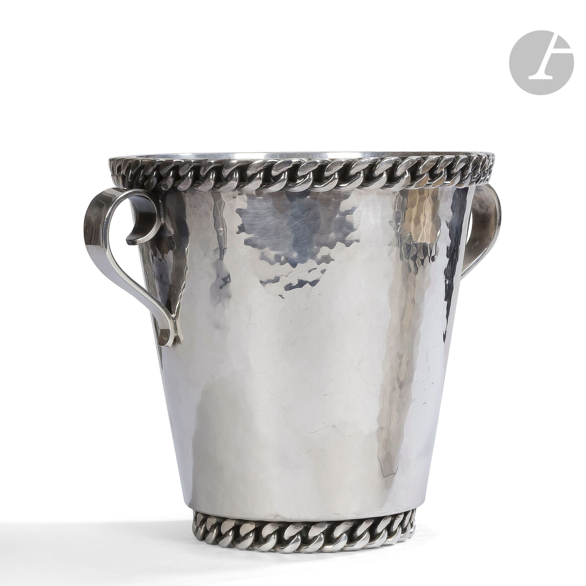 JEAN DESPRÉS (1889-1980)
Rare rafraîchissoir à demi-bouteille de Champagne en métal argenté.
Le corps tronconique est flanqué de deux anses en volutes et reçoit deux gourmettes décoratives à maillons plats en application ; l’une sur la base en retrait, l’autre sur le pourtour de la bordure.
Signé J. DESPRÉS à la pointe au revers de la base et porte le poinçon de Maître Orfèvre sur la gourmette de la partie basse.
Hauteur : 17,5 cm - Longueur : 22 cm

Provenance :
M. M., Avallon. Conseiller municipal sous l’ère du sénateur-maire Jean Chamand.

LOT VENDU SUR FOLLE ENCHÈRE
