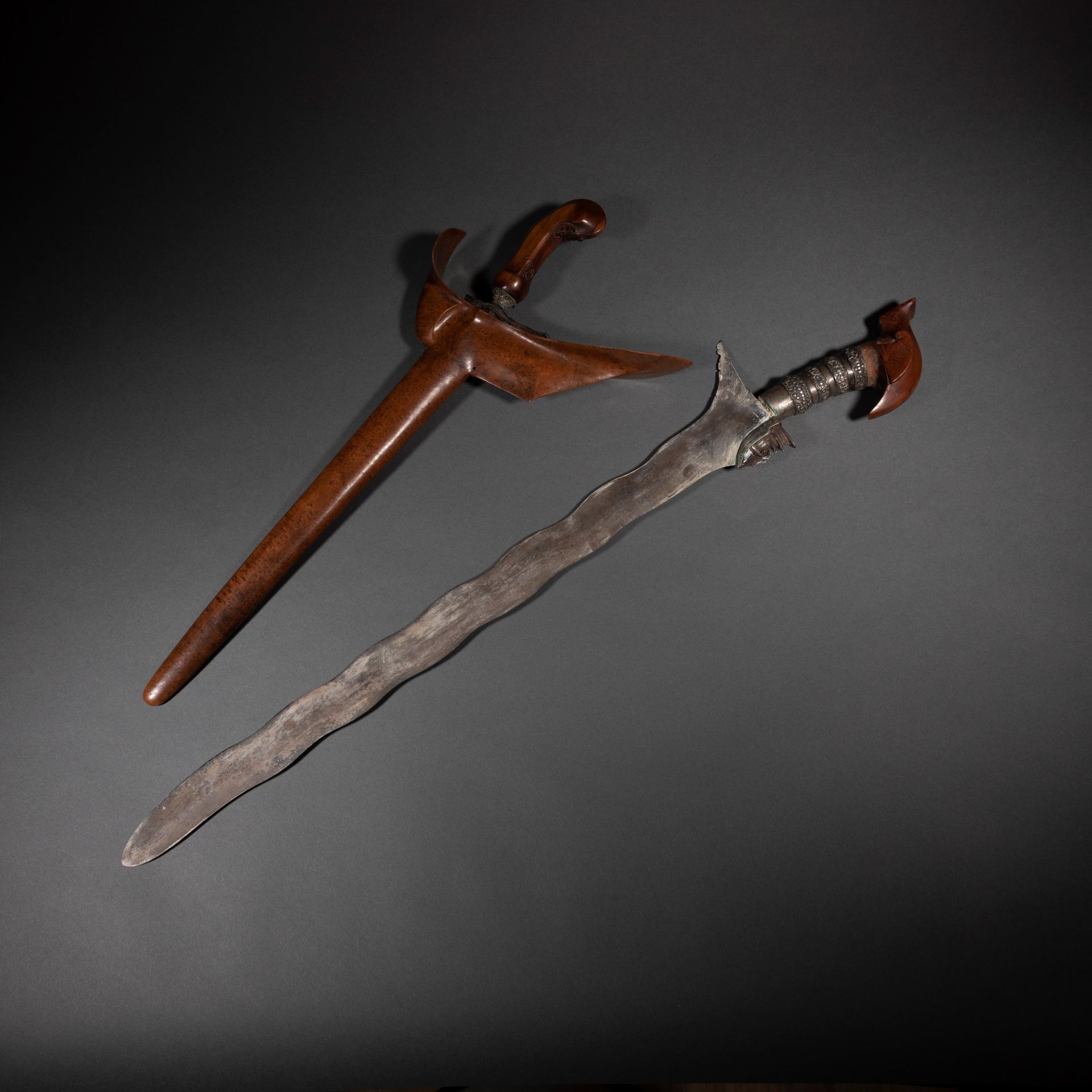 Un lot réunissant un kriss dans son fourreau en bois sculpté et un grand kriss ou sabre sudang à la lame ondulante et la poignée sculptée caractéristique des populations tausug de l’archipel de Sulu.

Java, et Sulawesi ou archipel de Sulu

Bois, fer, argent, oxydations, belles patines d’usage.

H. 49 cm et 71 cm



Provenance :

Collection Nadine Vinot-Postry, Paris.