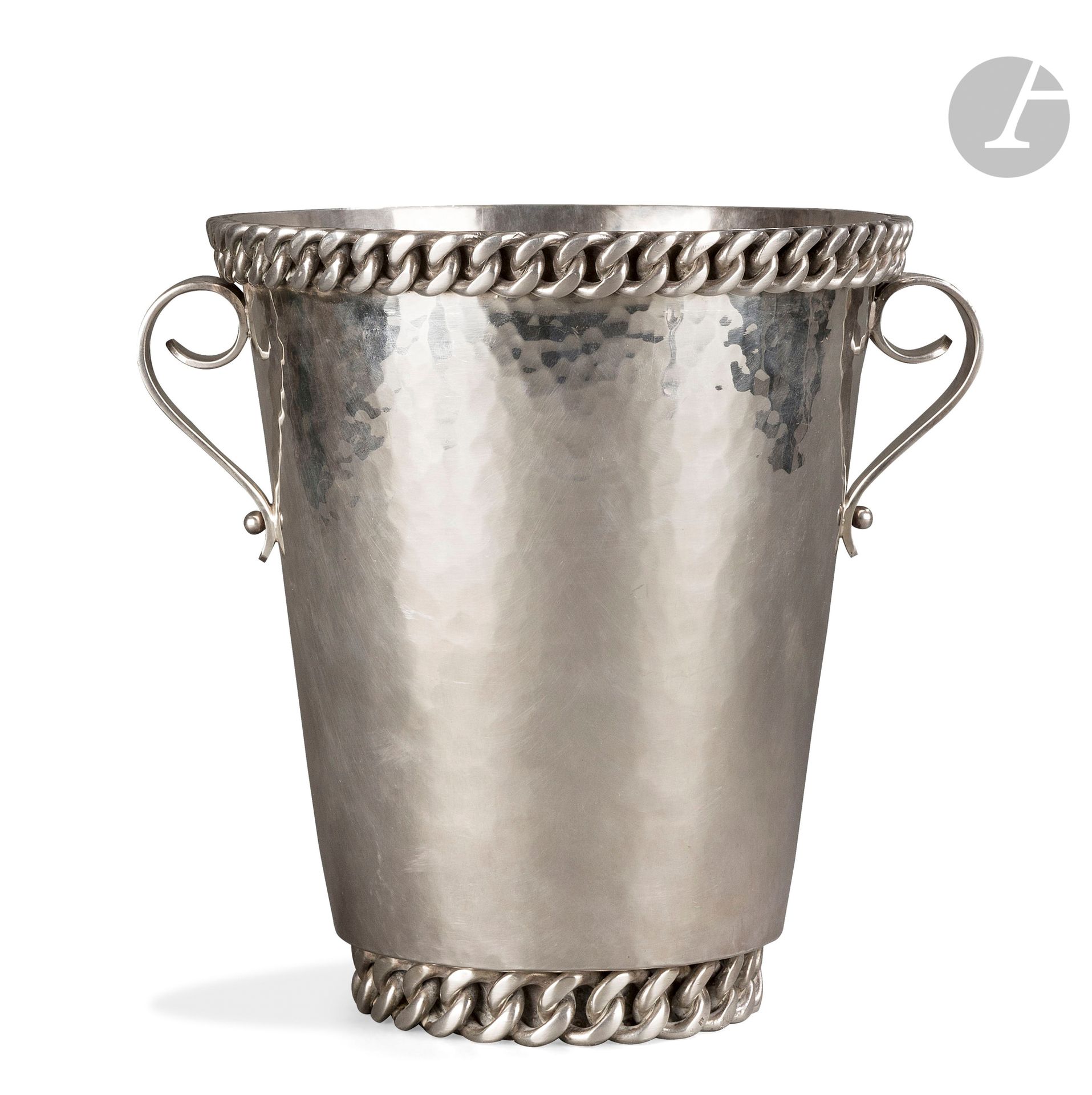 JEAN DESPRÉS (1889-1980)
Modernist champagne bucket in silver plated metal. The body with hammered surface receives two scrolled grips, treated smooth, and hosts a first and large curb chain with flat links on the recessed heel and a second on the edge of the rim. Signed J. DESPRÉS at the point under the base and bears the hallmark of Master Goldsmith on the curb chain of the base. H. 25 cm

Provenance :
Private collection, Neuilly.